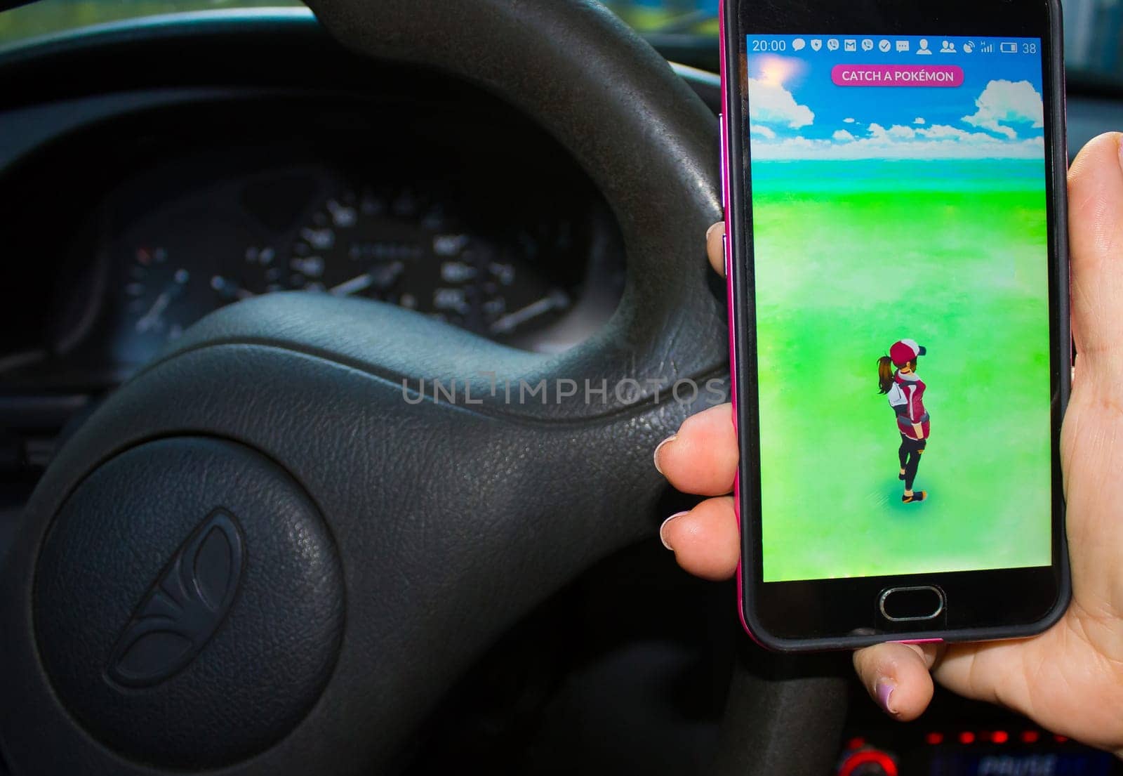 Dnipropetrovsk, Ukraine - July 23, 2016: The female hand holding phone with game Pokemon GO - a free-to-play augmented reality mobile game developed by Niantic for iOS and Android devices inside the car.