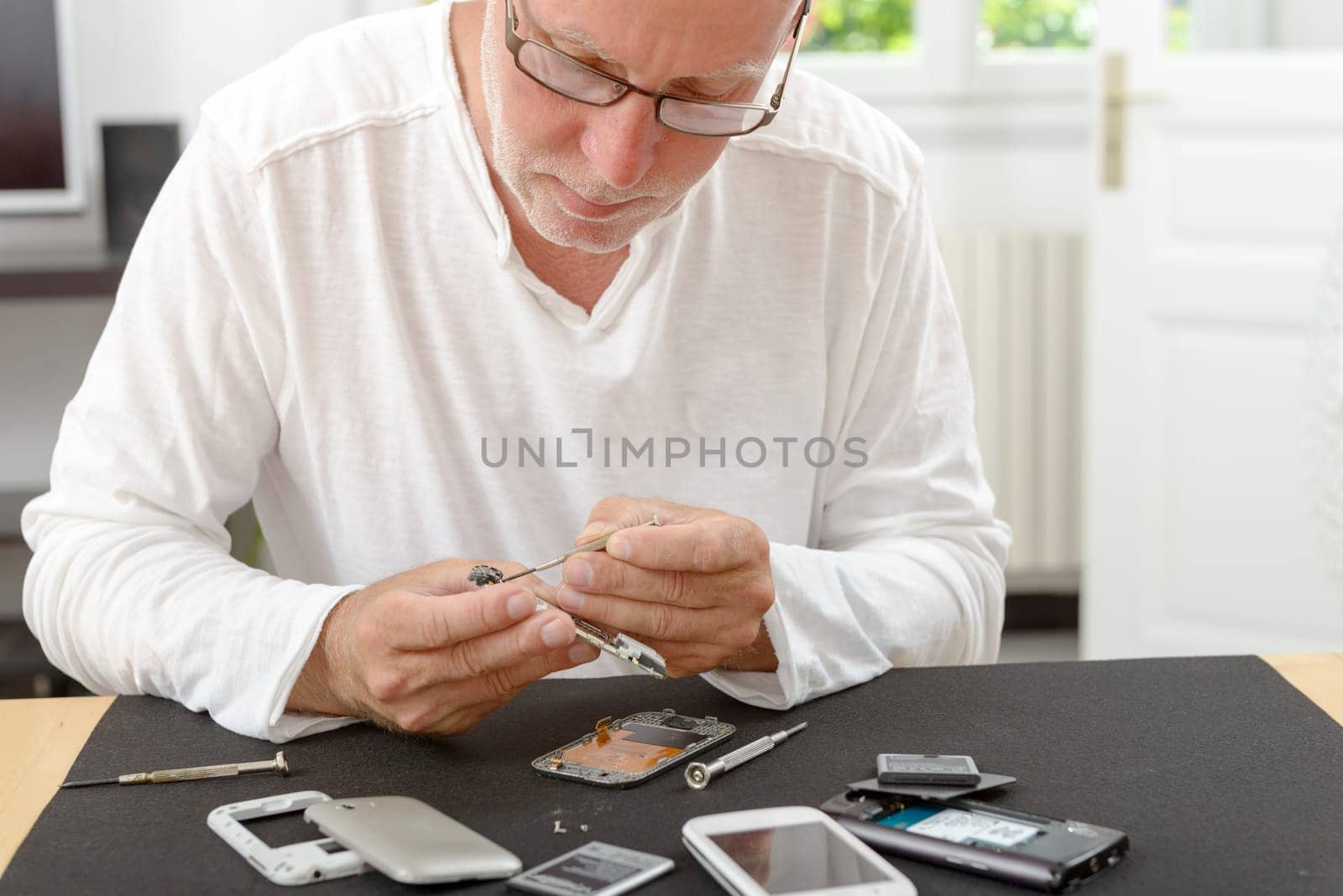 a mature man repaired a smartphone in his home