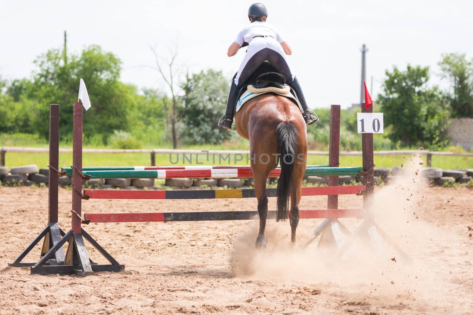 Volgograd, Russia - June 19, 2016: Back view of a horse with a rider during take-off when jumping through a barrier