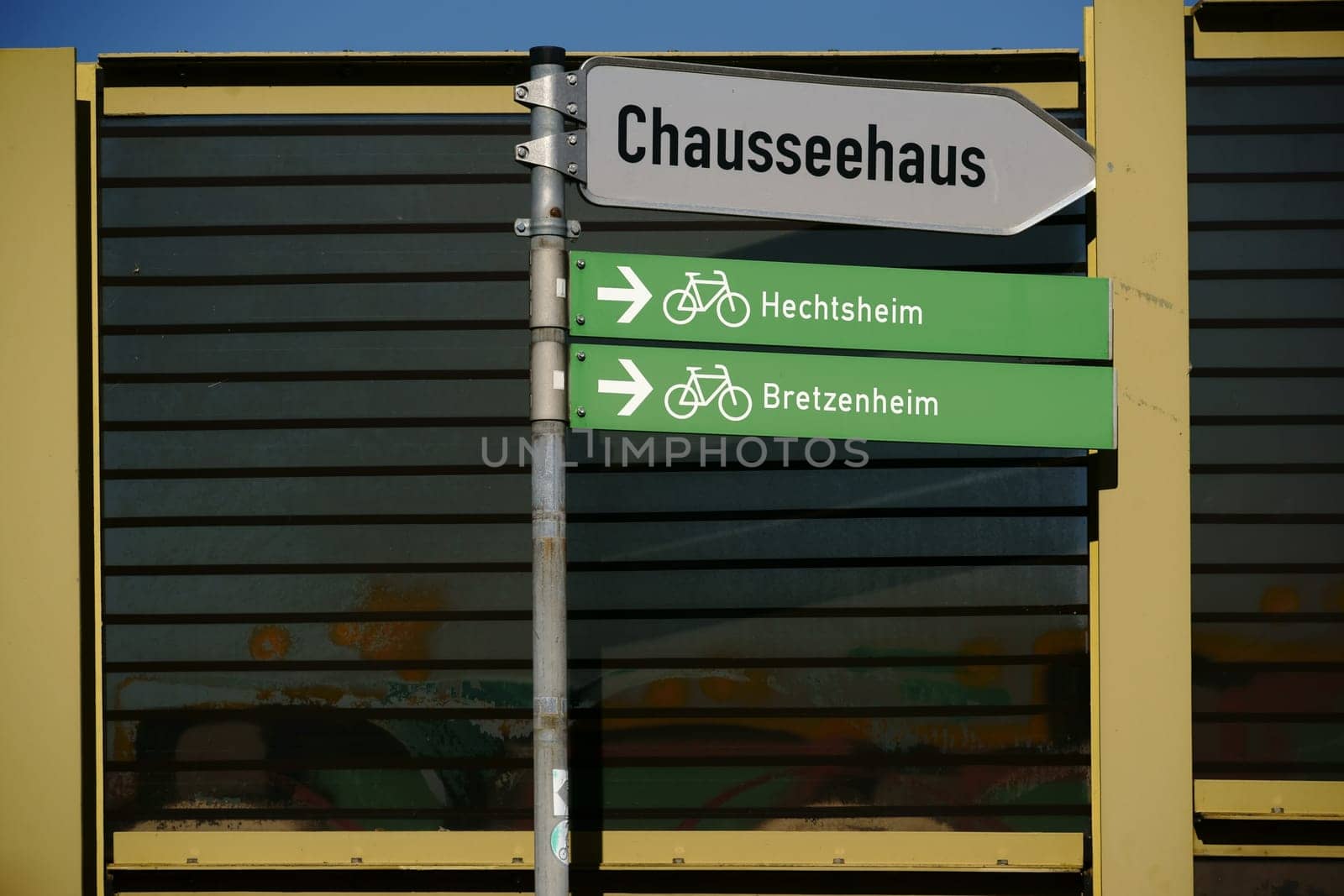 Traffic signs for cycle paths as well as information signs stand in front of a soundproofing wall.