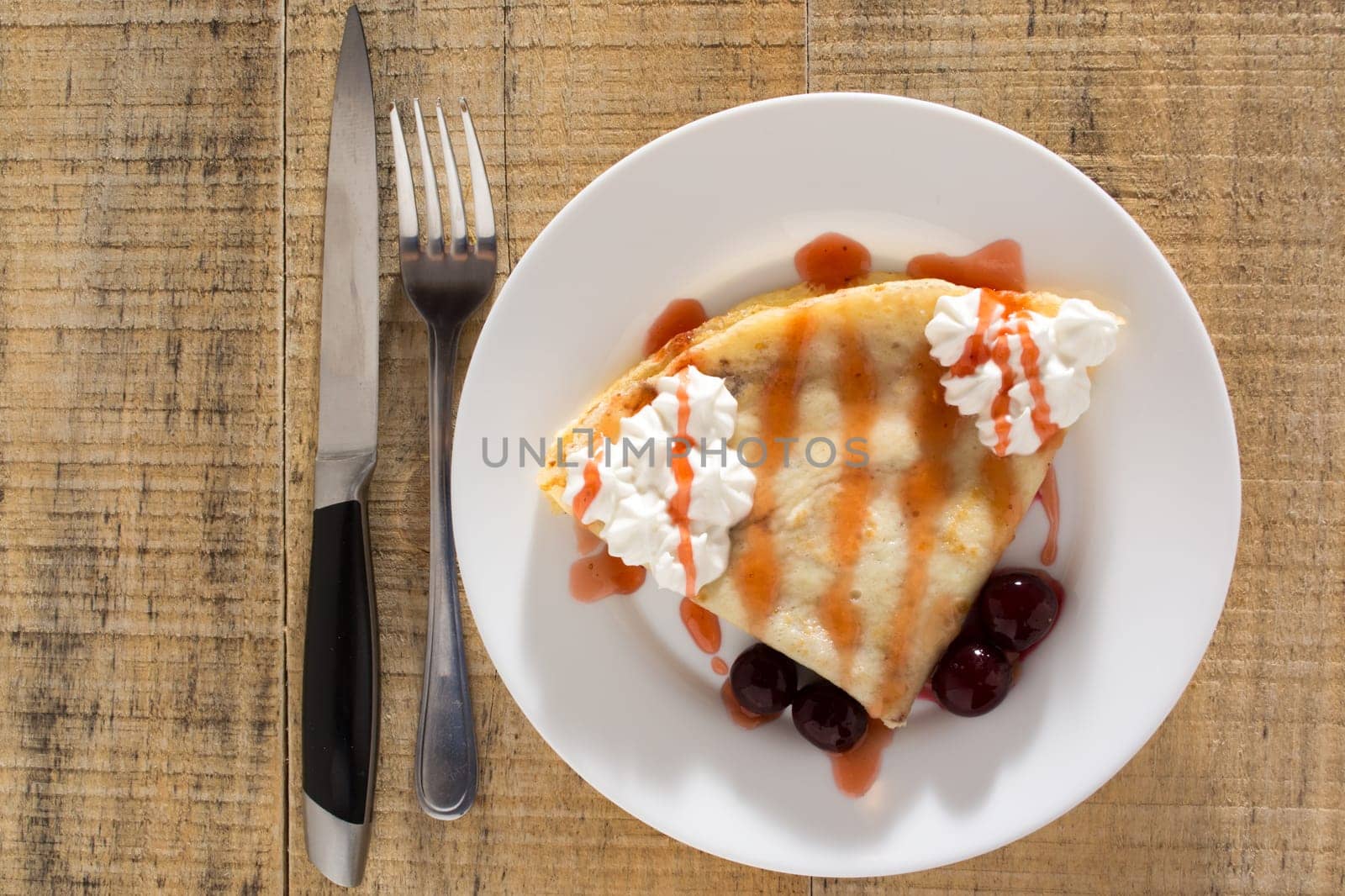 Fresh pancakes with cherry arranged on wooden table