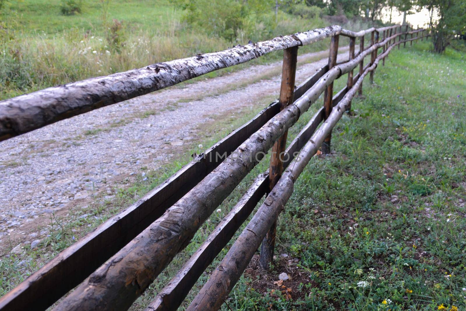 Old rural wooden fence on the road troug the woods