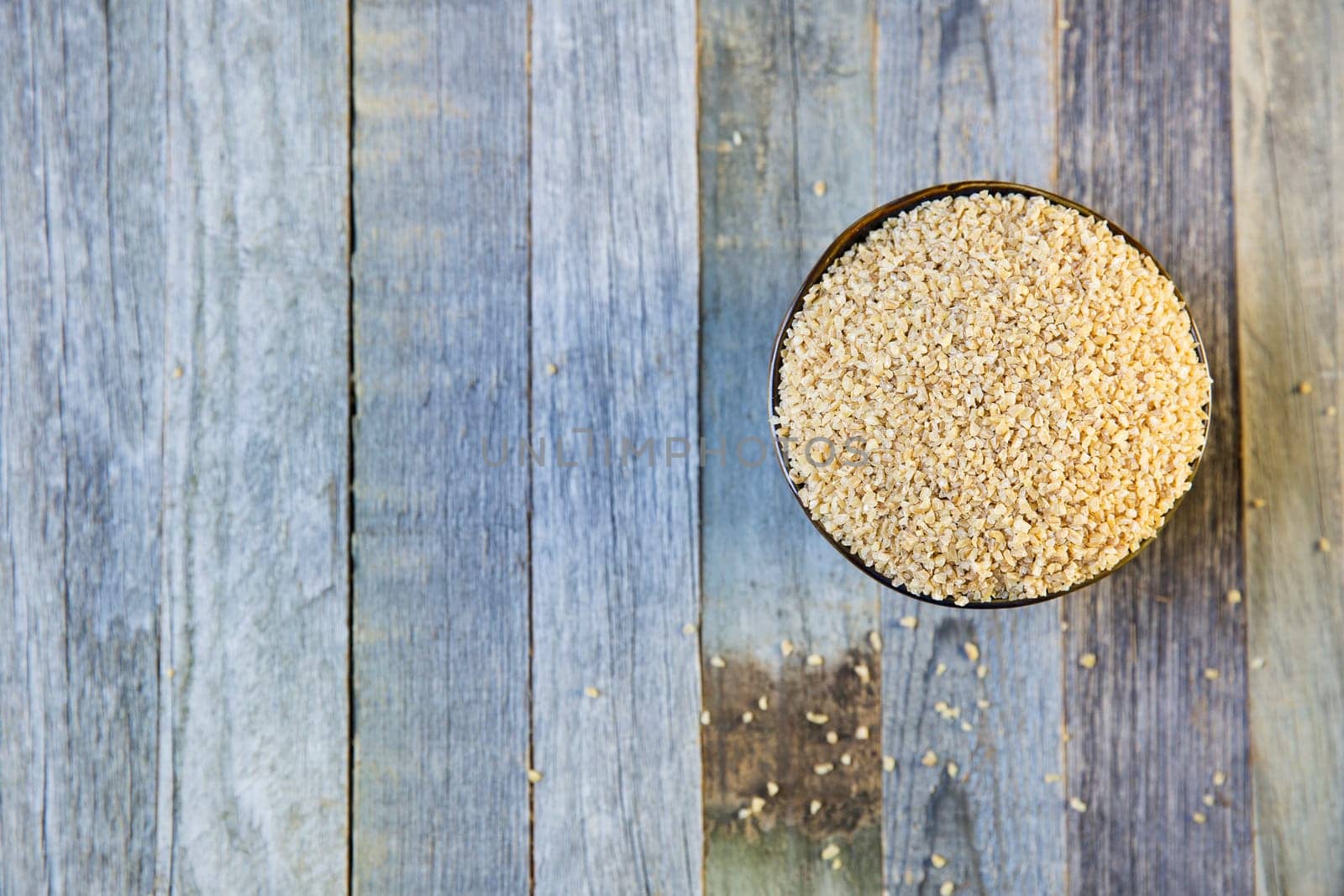 Bowl of bulgur and rolled oats in a row viewed from above on an old wooden table, with copy space