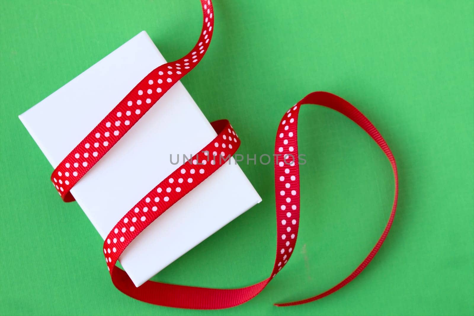 Small Christmas gift box and ribbon on green background