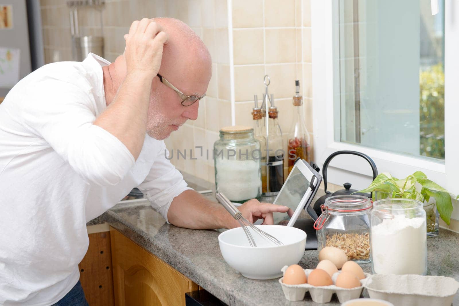 a senior man in kitchen using digital tablet