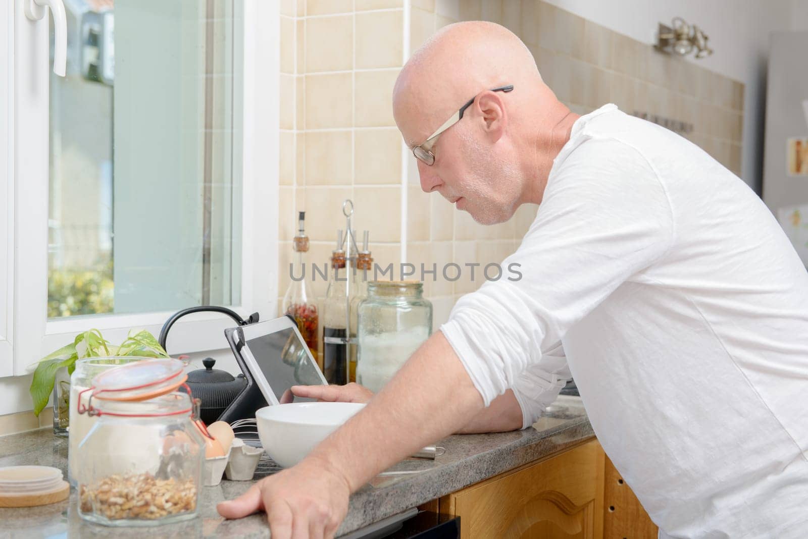 a senior man in kitchen using digital tablet