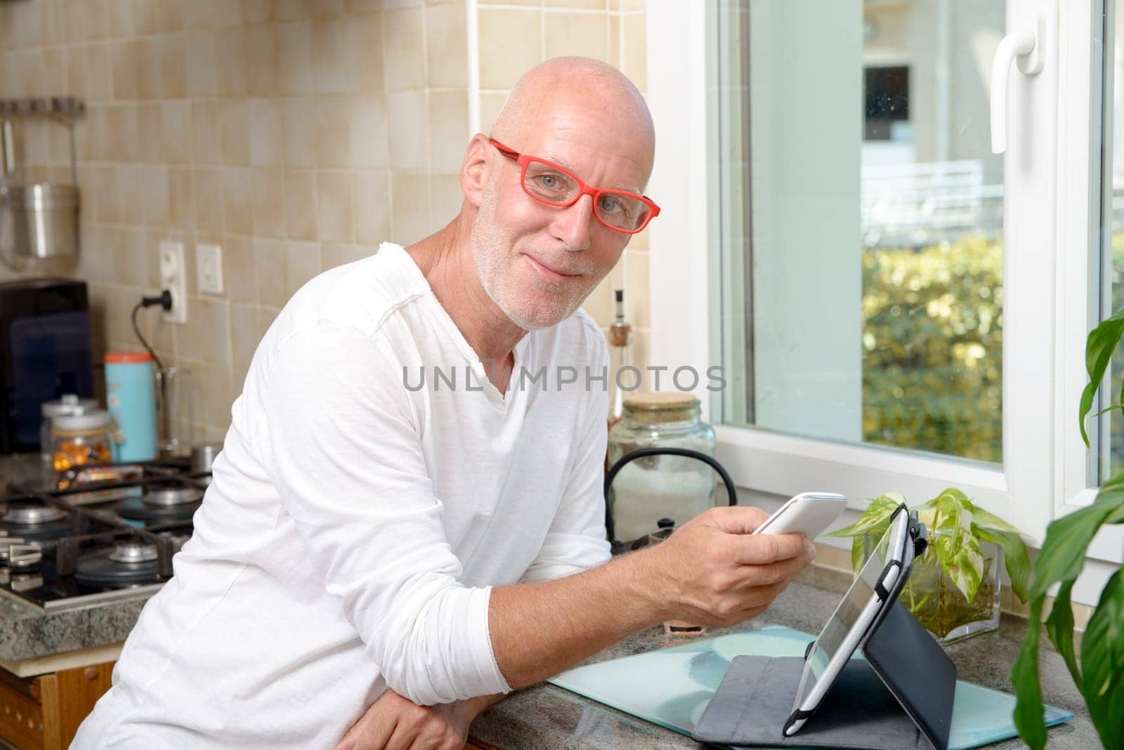 a middle-aged man with a mobile phone in his kitchen