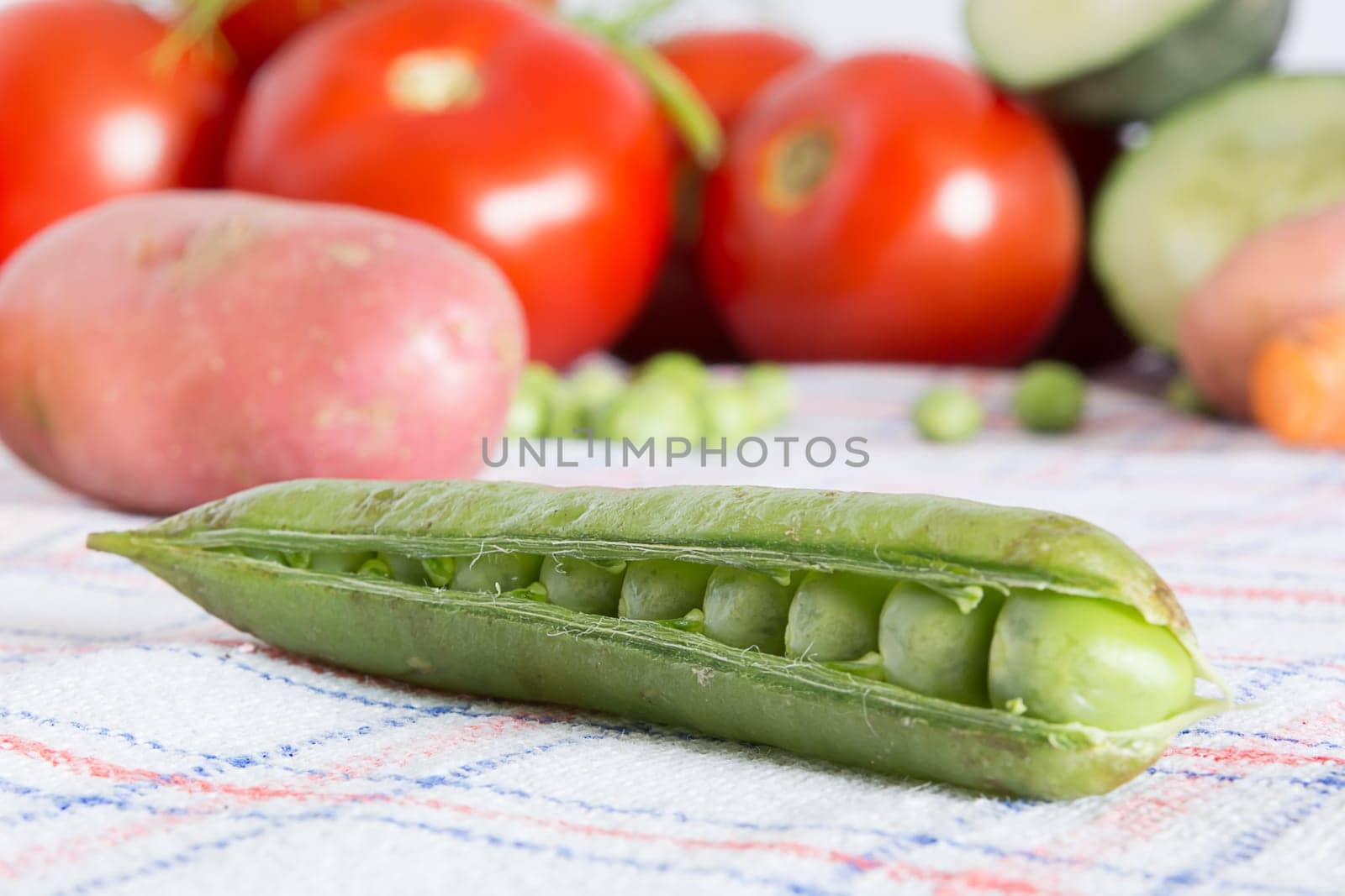 Green beans on a kitchen table with blurred background with other vegetables