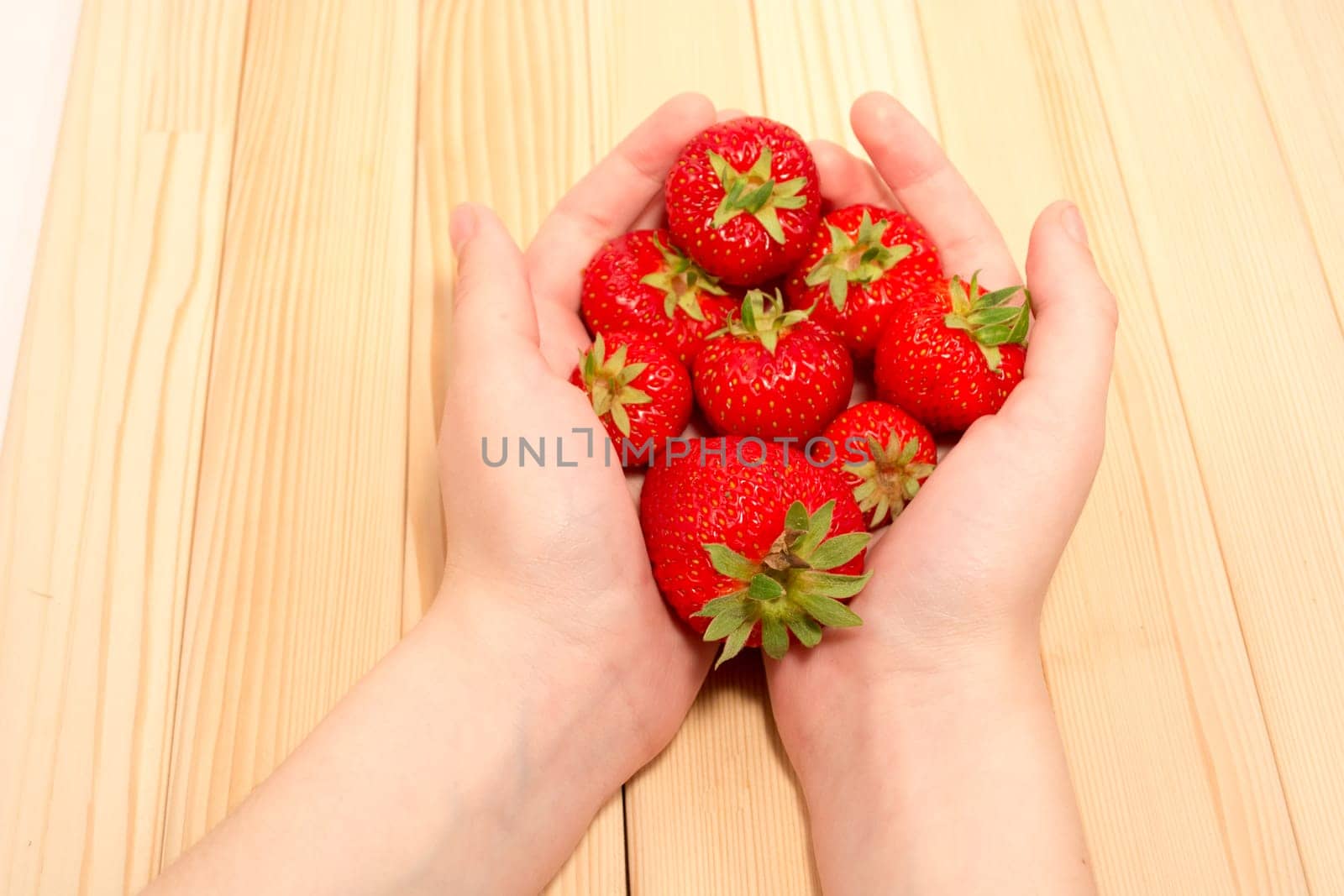 Child hands holding fresh strawberries