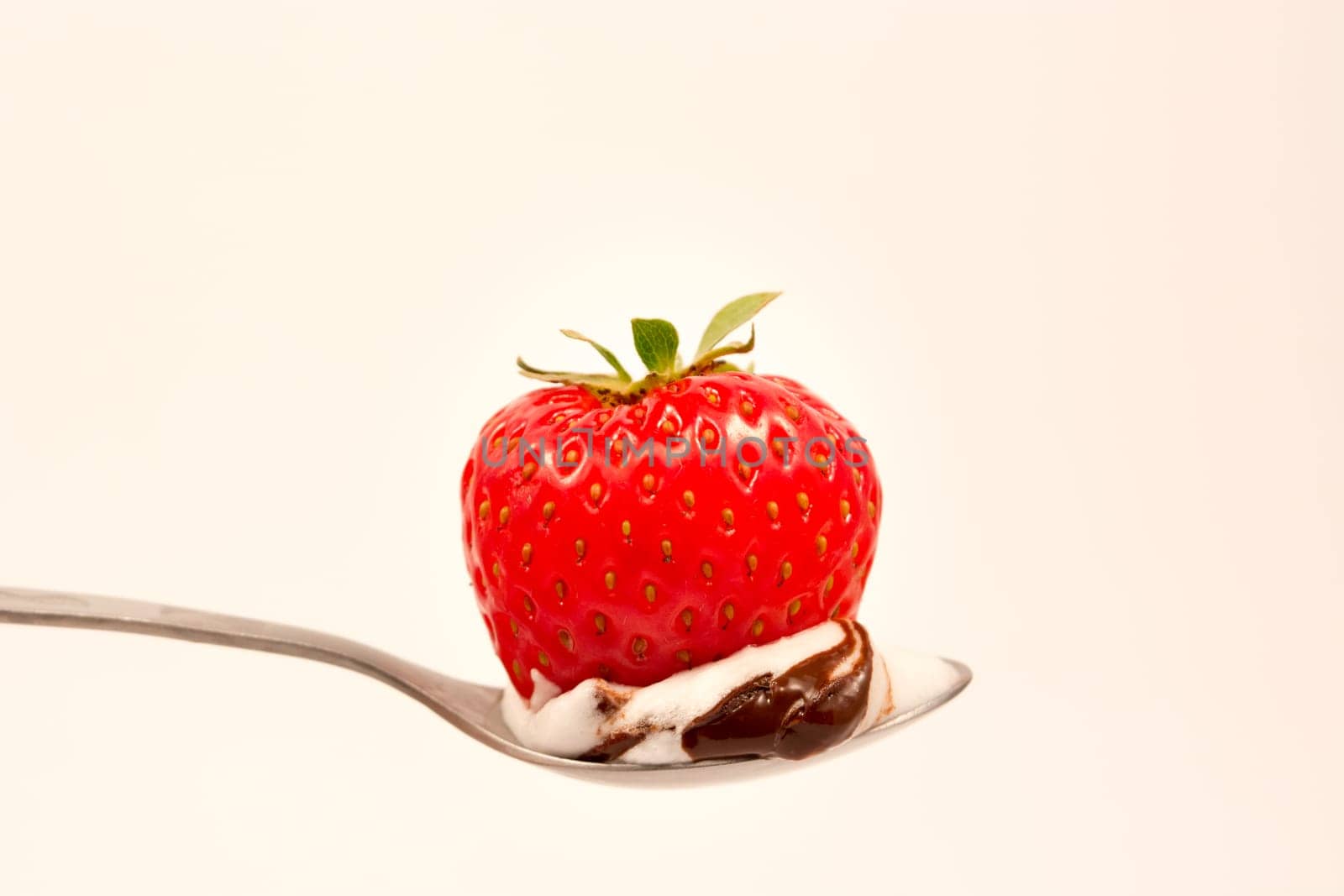 Spoon with strawberry in chocolate and vanilla cream
