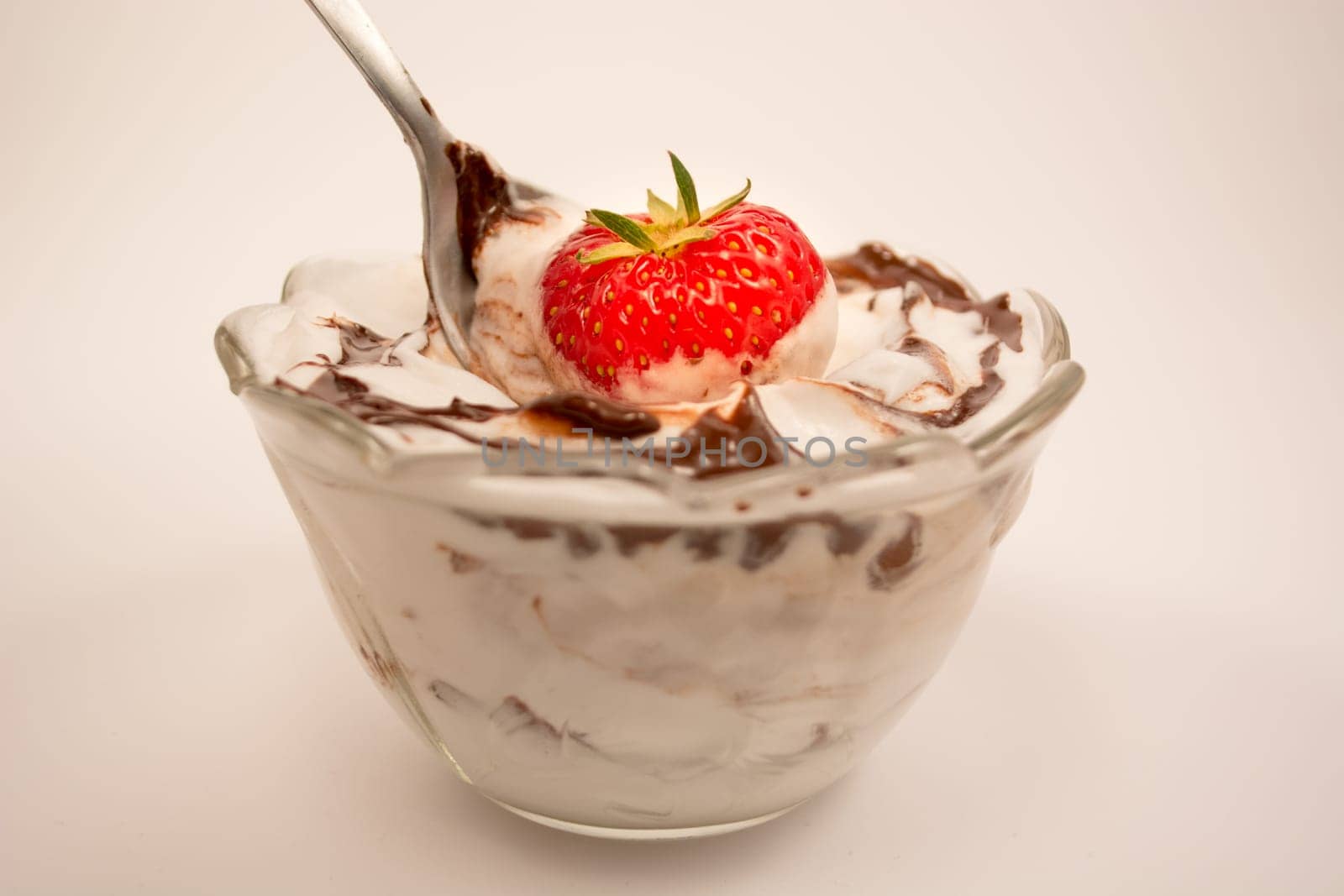 Spoon taking out strawberry from desert