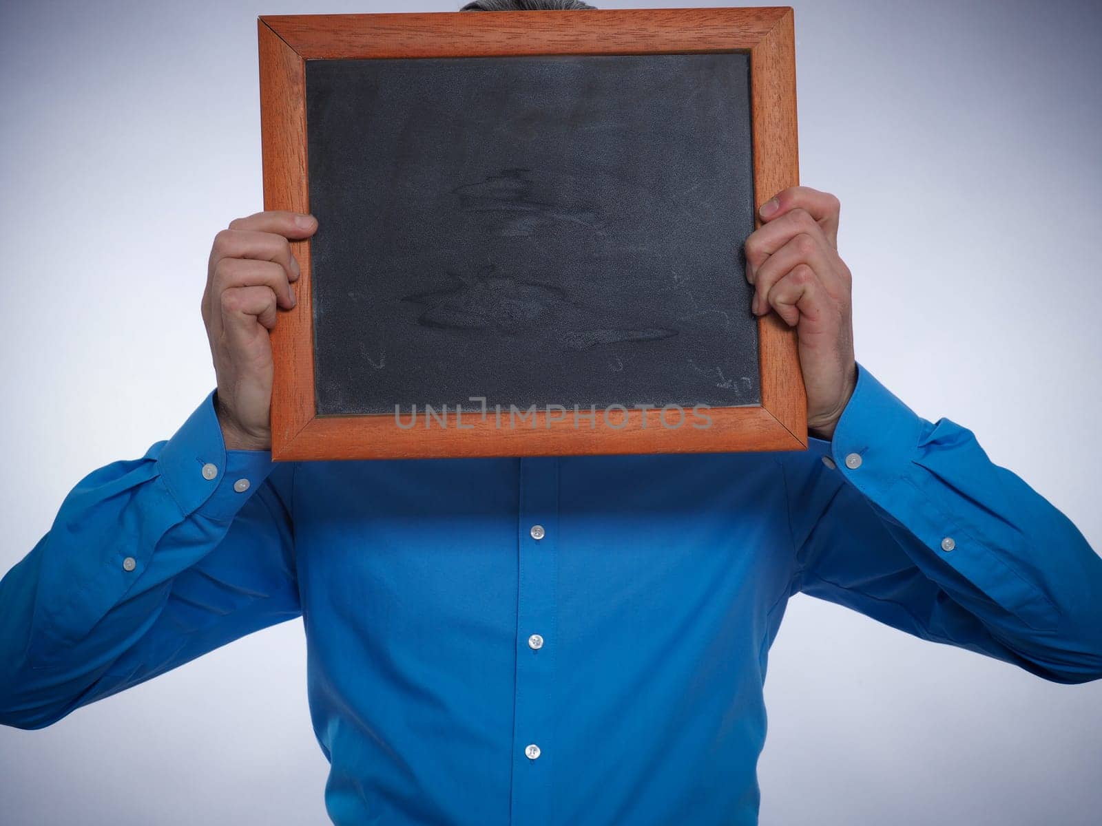 Businessman hiding his face behind a small chalkboard with space for text or image