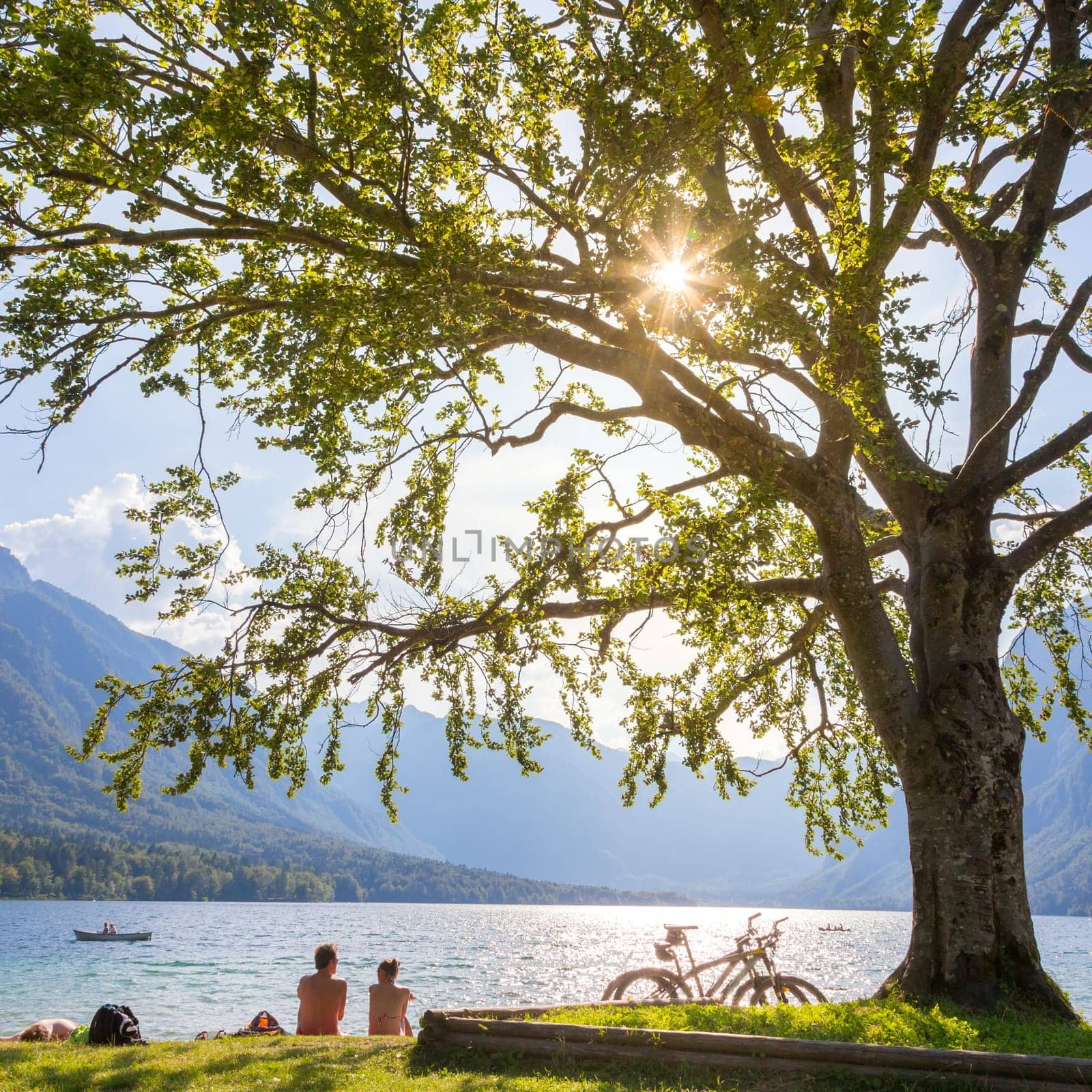 Active sporty couple relaxing on lake beach after active day of cycling enjoying beautiful nature around lake Bohinj, Slovenia.