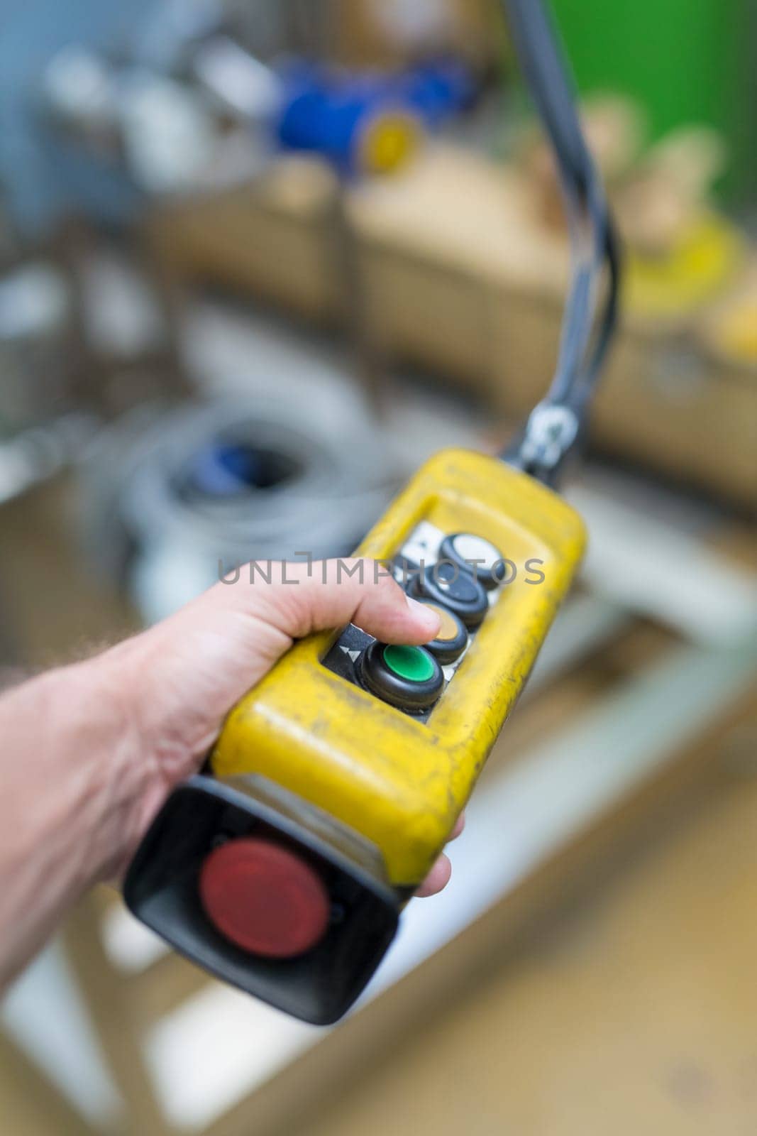 Industrial worker pushing on button of machinery control panel in manufactury.