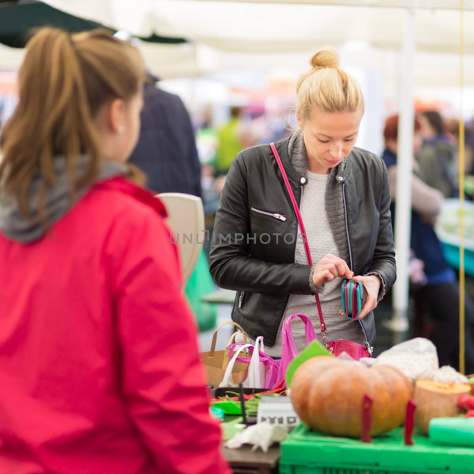 Woman buying fruits and vegetables at local food market. Market stall with variety of organic vegetable.