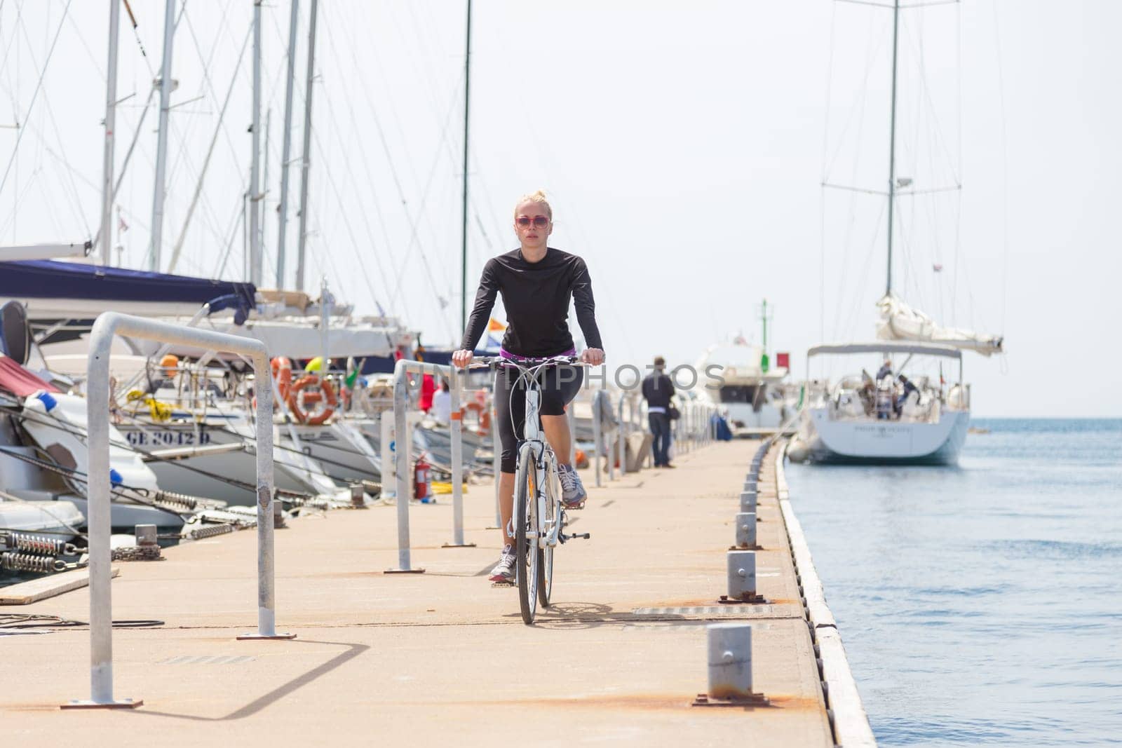 Young active woman cycling on pier in Rovinj marina, Istria, Croatia