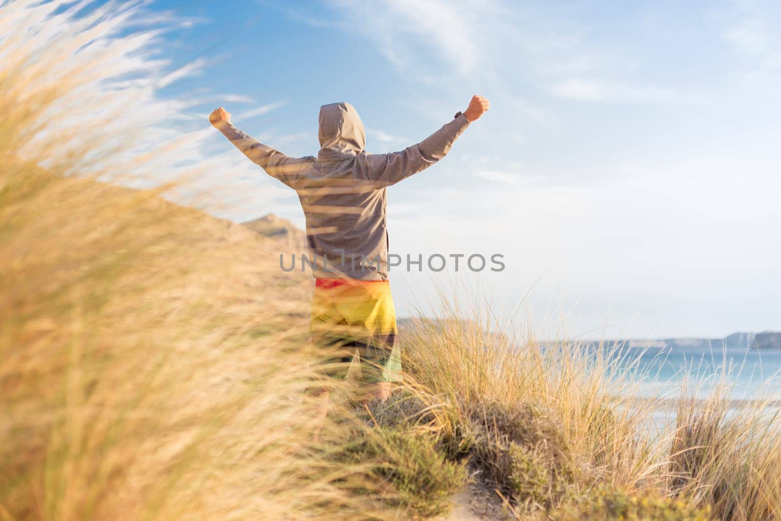 Successful sporty active man, arms raised, enjoying beauty of nature, freedom and life at beautiful landscape at Balos beach, Greece. Active lifestyle outdoors. Made it.