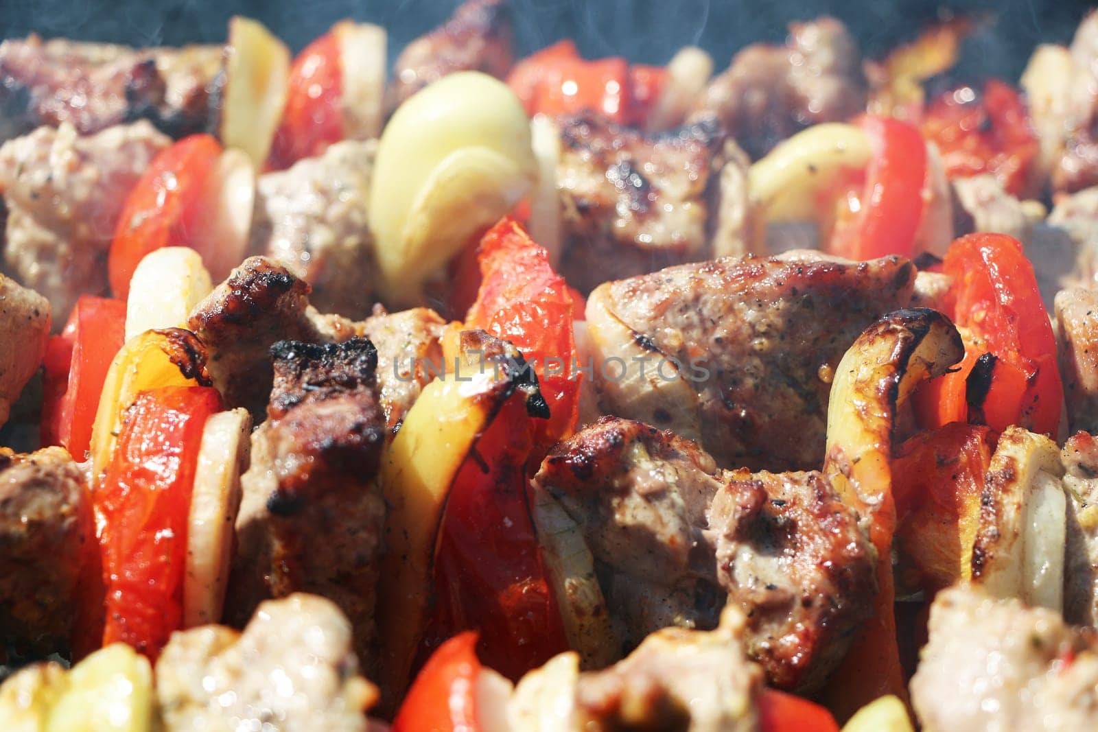Meat and vegetables cook grilled macro on charcoal on a background of a smoke, close-up