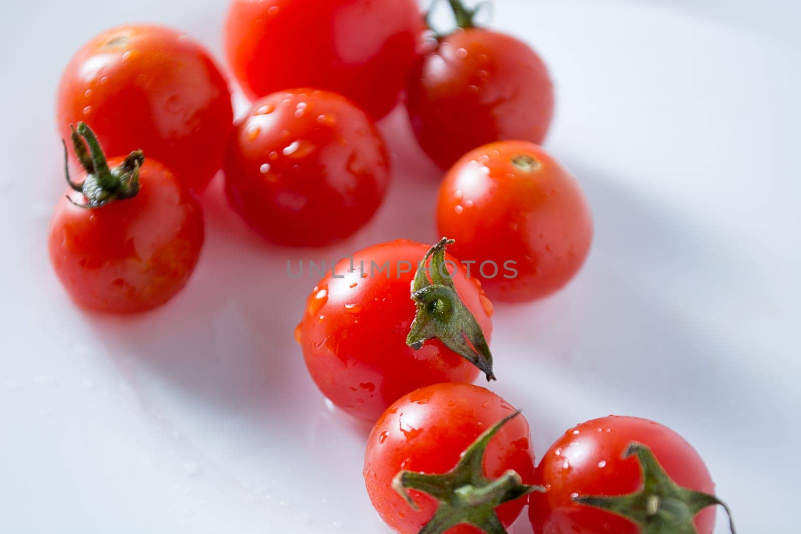 Ripe and red cherry tomatoes in white plate isolated on white background