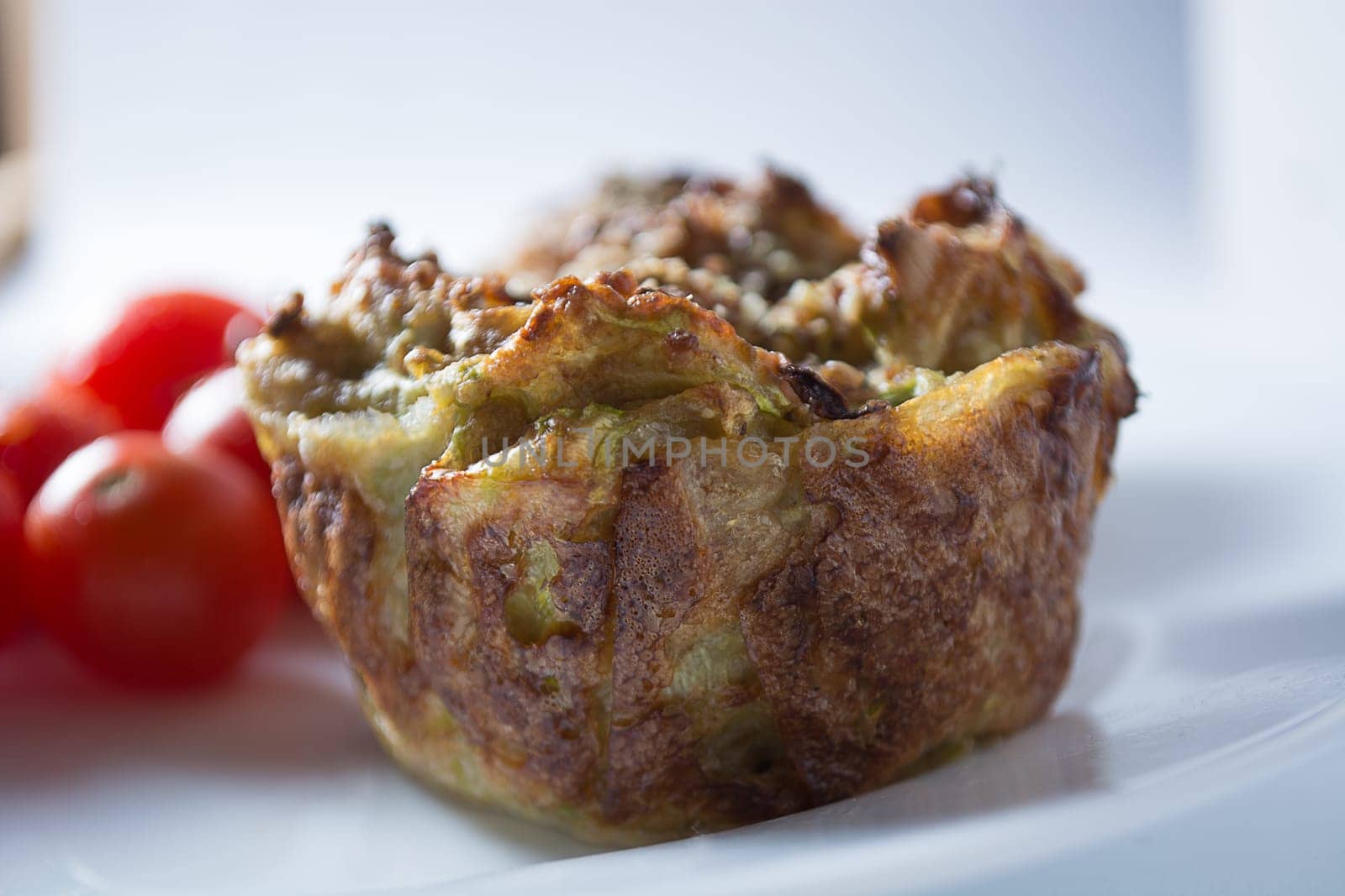 Ripe and red cherry tomatoes with zucchini muffins in white plate isolated on white background