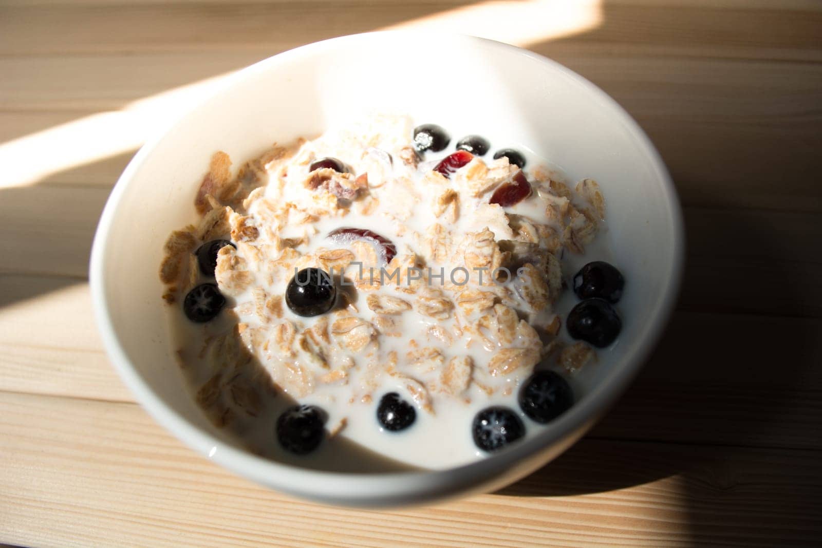 White bowl with healthy breakfast. Aronia and other berries with spelta  in milk