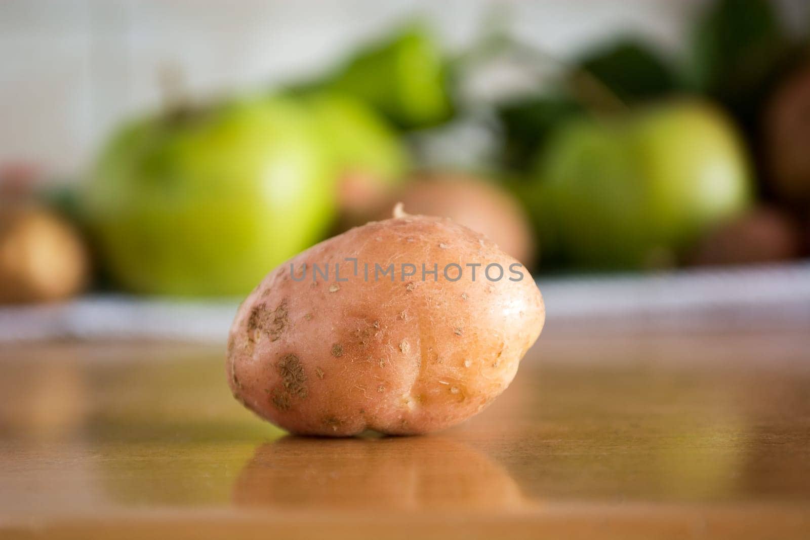CLoseuo of the potato on the kitchen table with various vegetables in the background