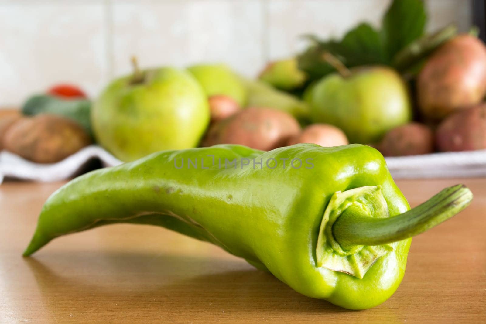 CLoseuo of the green pepper on the kitchen table with various vegetables in the background