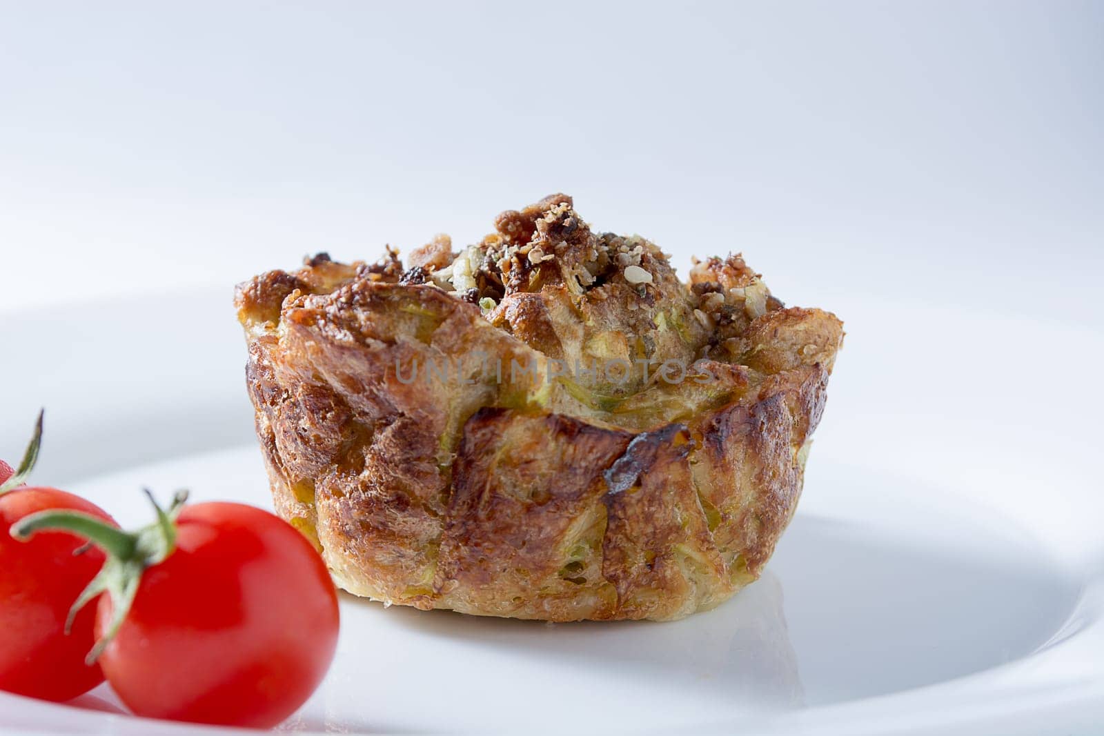 Ripe and red cherry tomatoes with zucchini muffins in white plate isolated on white background