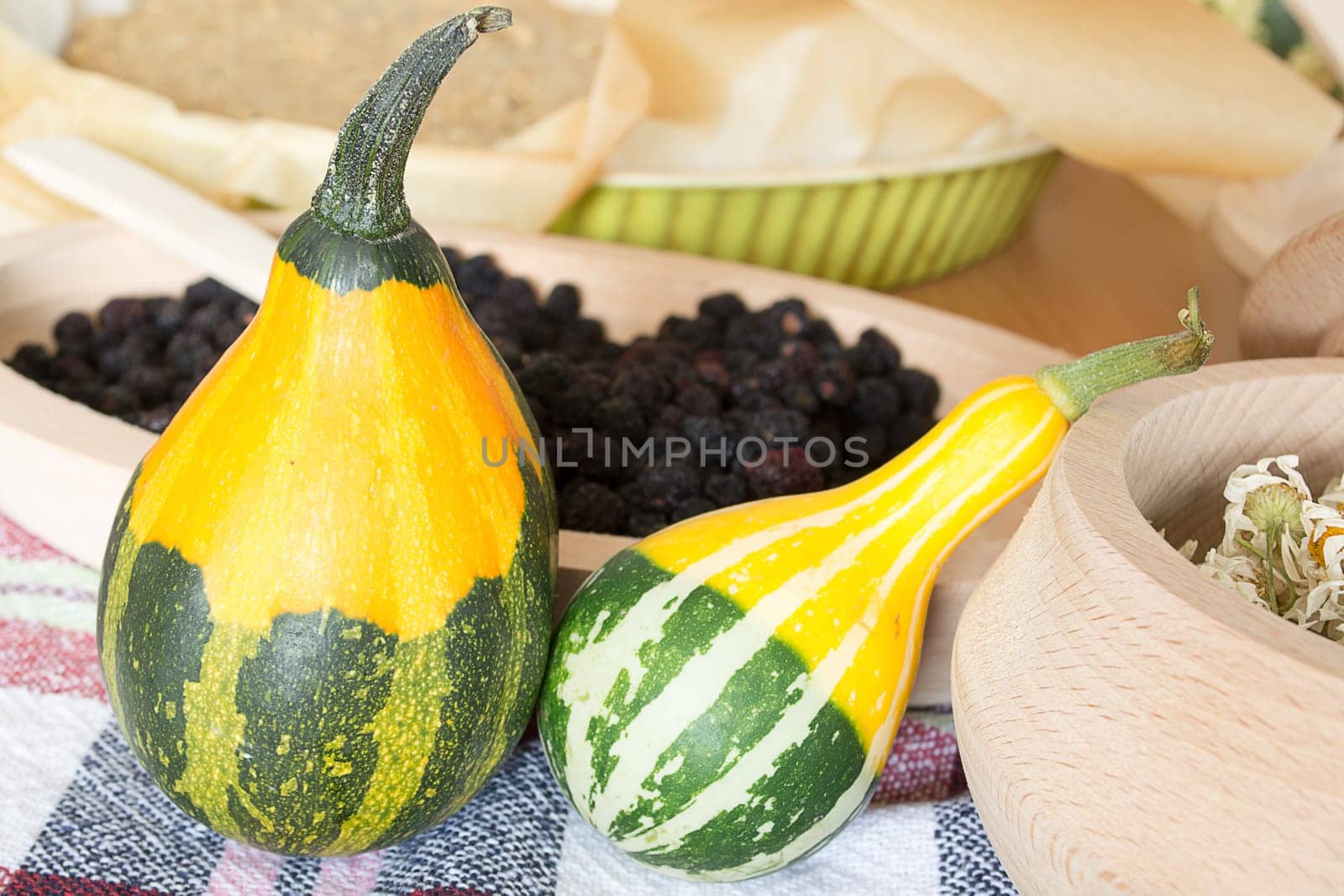 Decorative pumpkins on kitchen table with dryed chamomile in wooden bowl