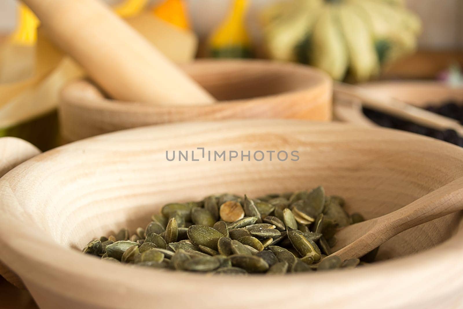 Wooden bowl with pumpkin seeds and wooden spoon in it