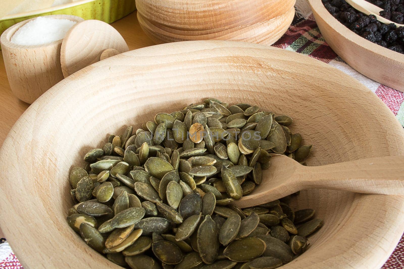 Wooden bowl with pumpkin seeds and wooden spoon in it