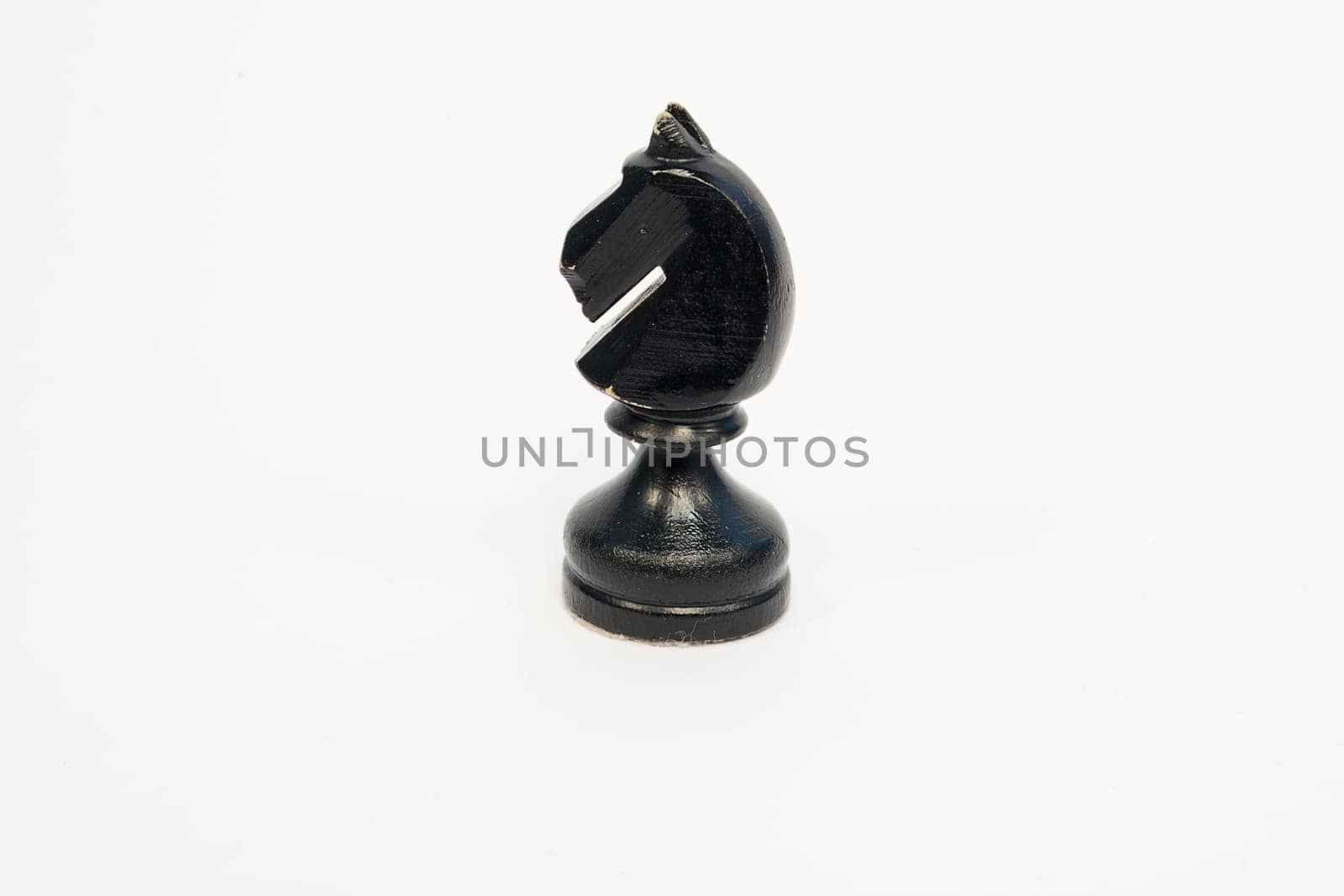 Old wooden chess piece black knight isolated on white background
