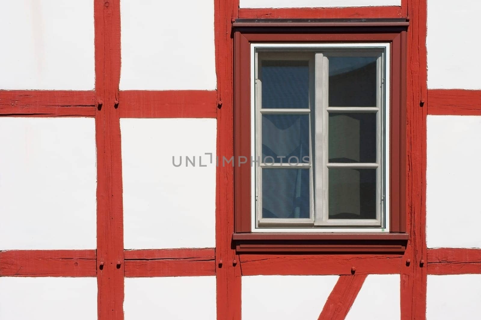 The close-up of the beam construction of a half-timbered house with window.
