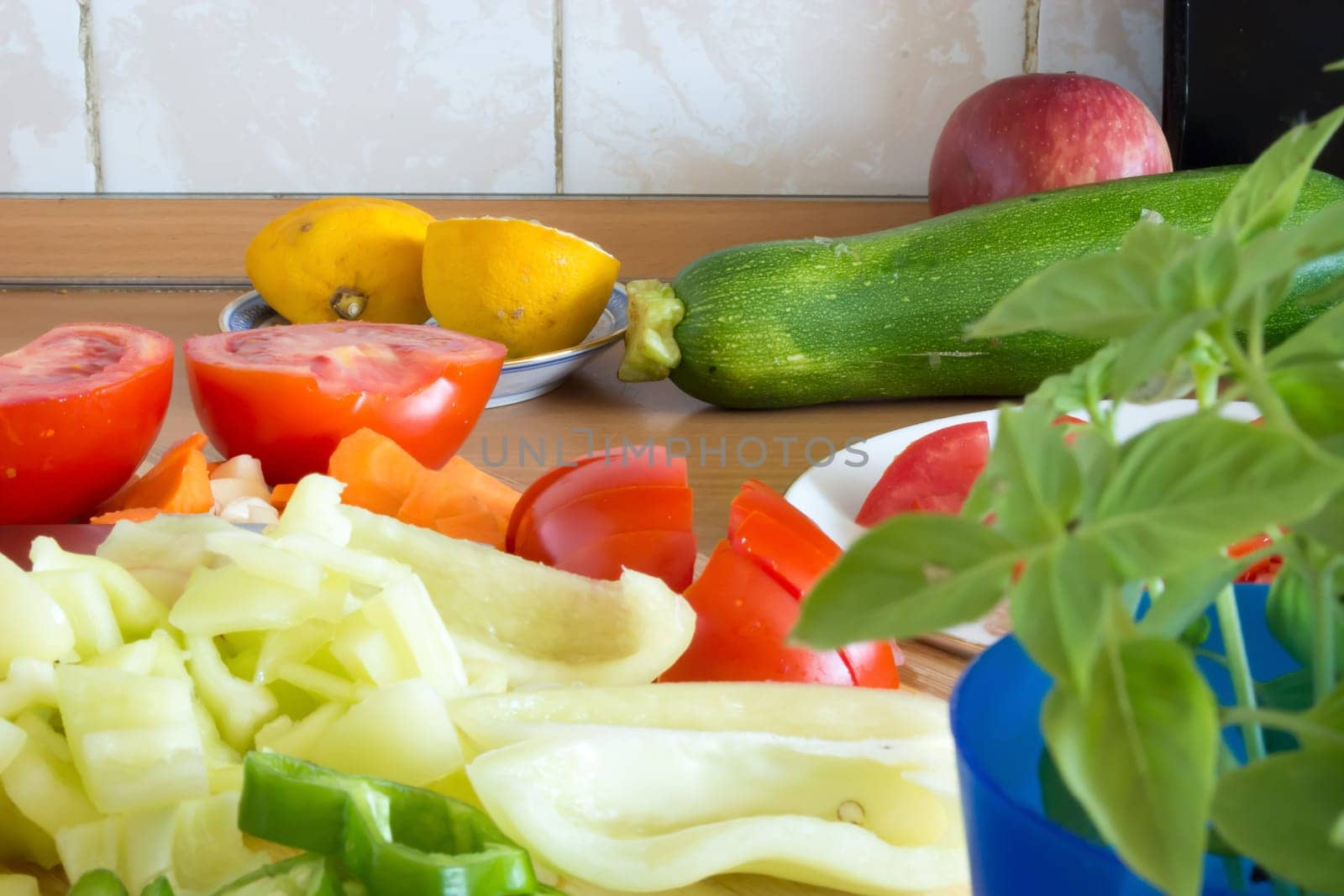 Kitchen full of various vegetables. Pepper, tomatoes sliced and ready to be boiled