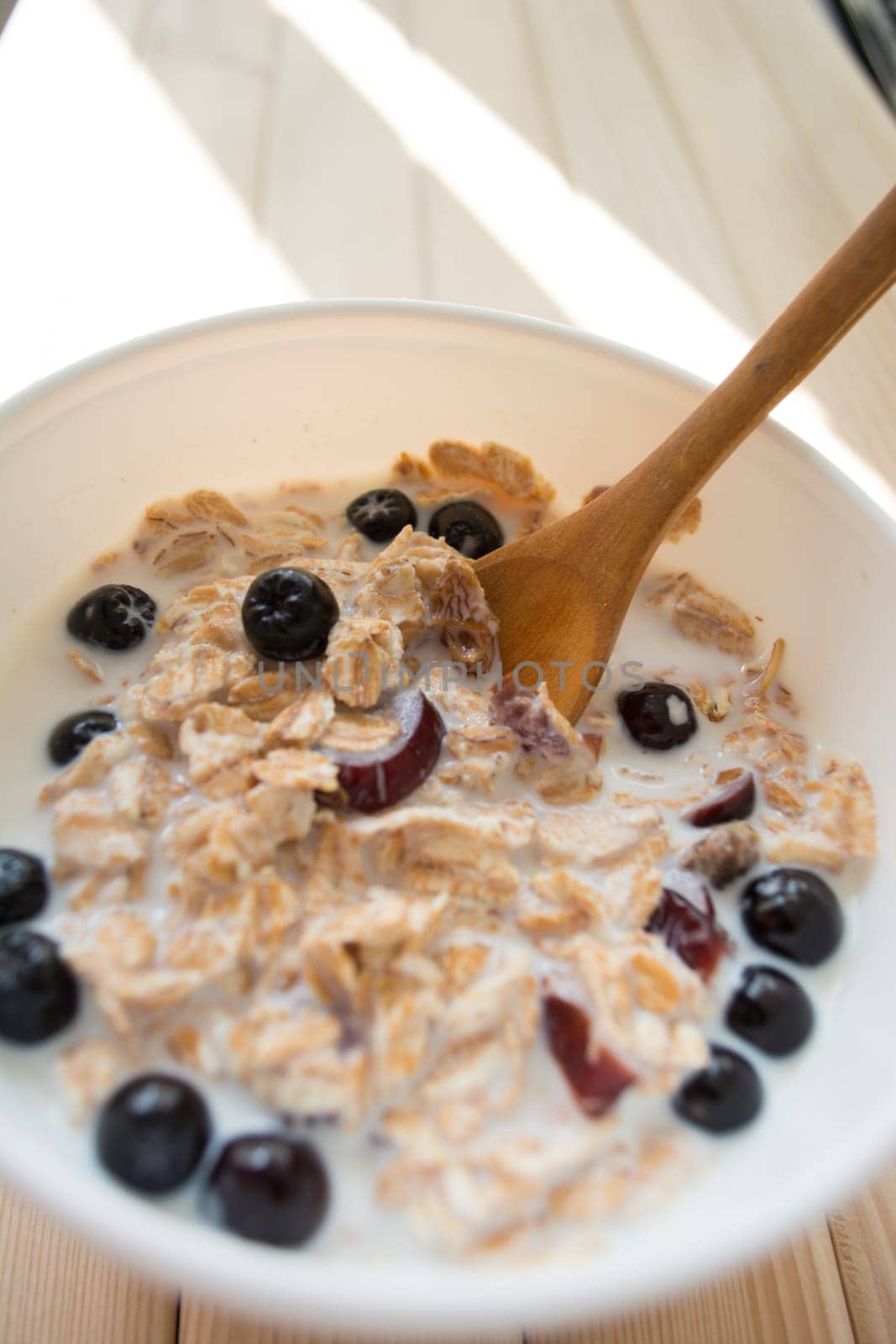 White bowl with healthy breakfast. Aronia and other berries with spelta  in milk