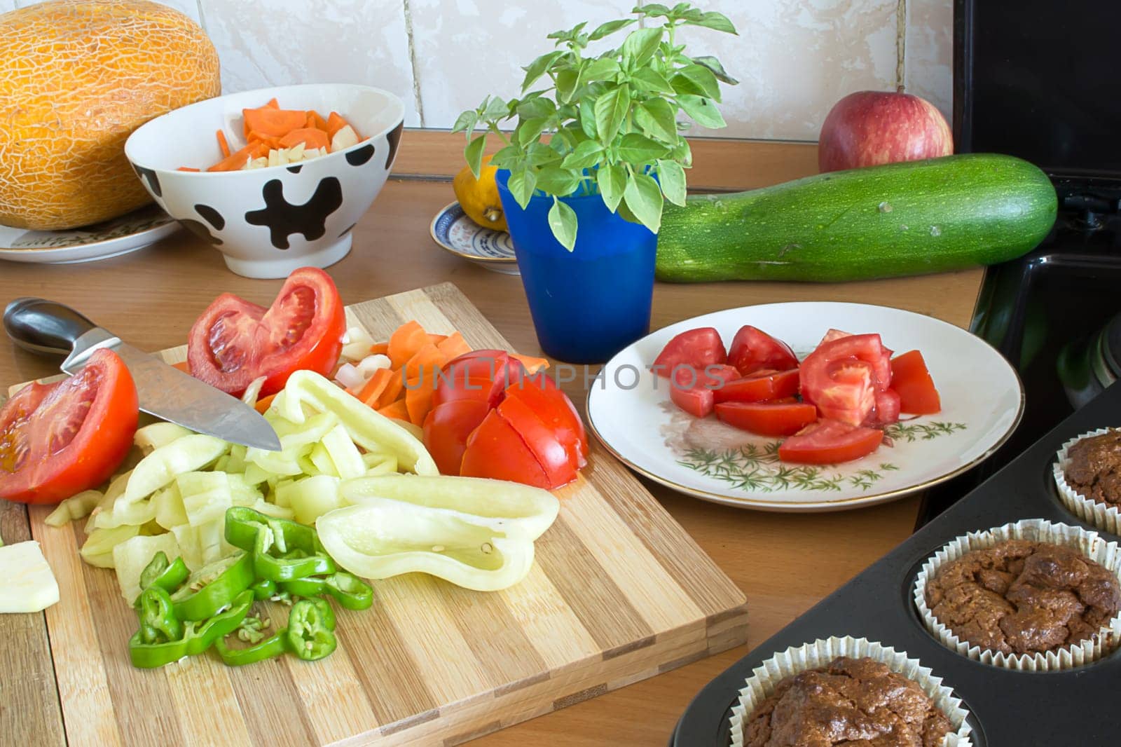 Kitchen full of various vegetables. Pepper, tomatoes sliced and ready to be boiled