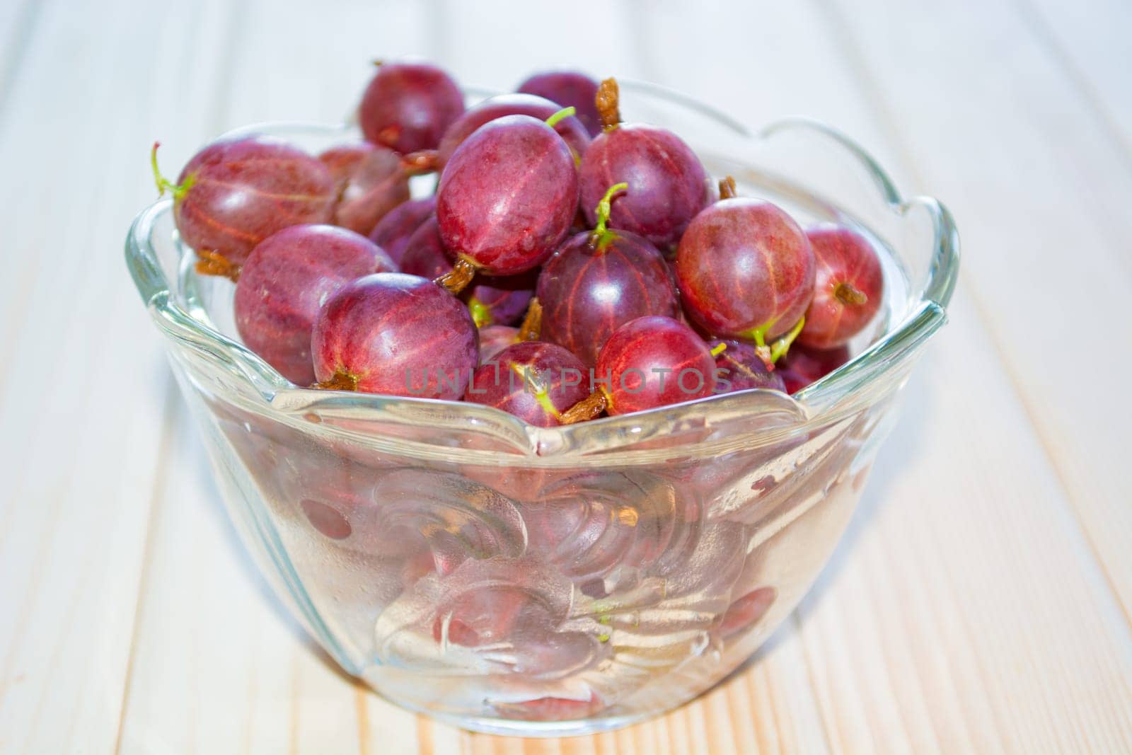 Gooseberry in glass bowl on the kitchen table. Blurred background