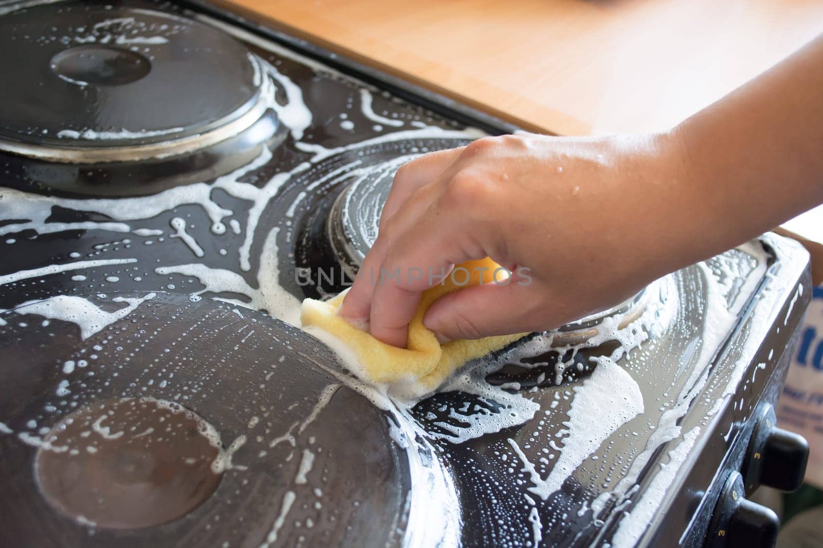 Close up of woman cleaning cooker at home kitchen