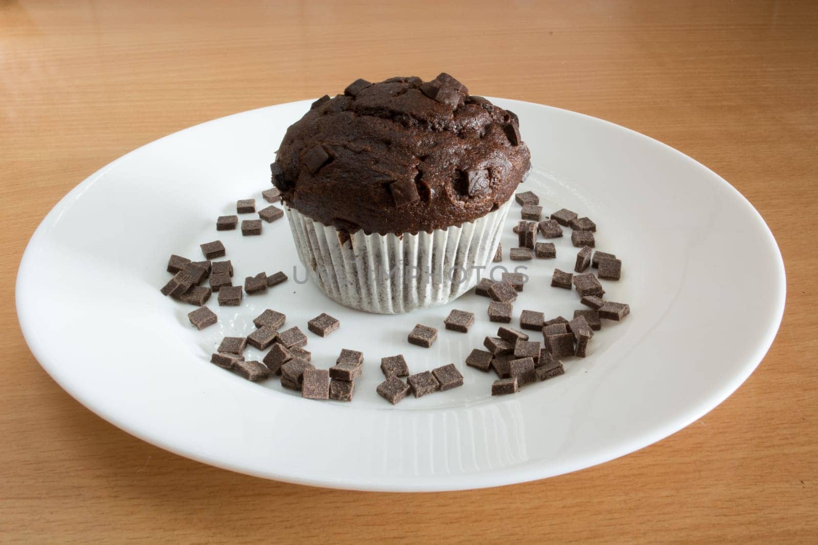 Isolated sweet chocolate cupcake in white plate. Plate and cupcakes are covered with chocolate crumbs