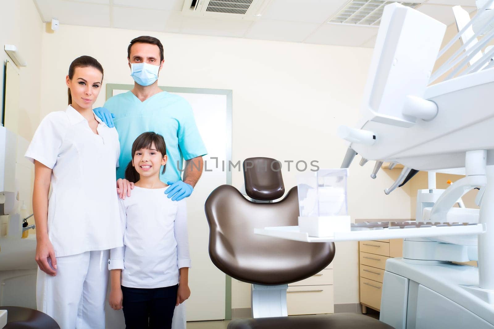 A dentist with his assistant taking care of a little girl..