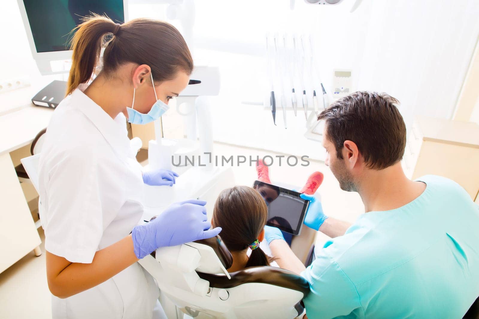 A little girl at the dentist getting a explanation with a Tablet PC..