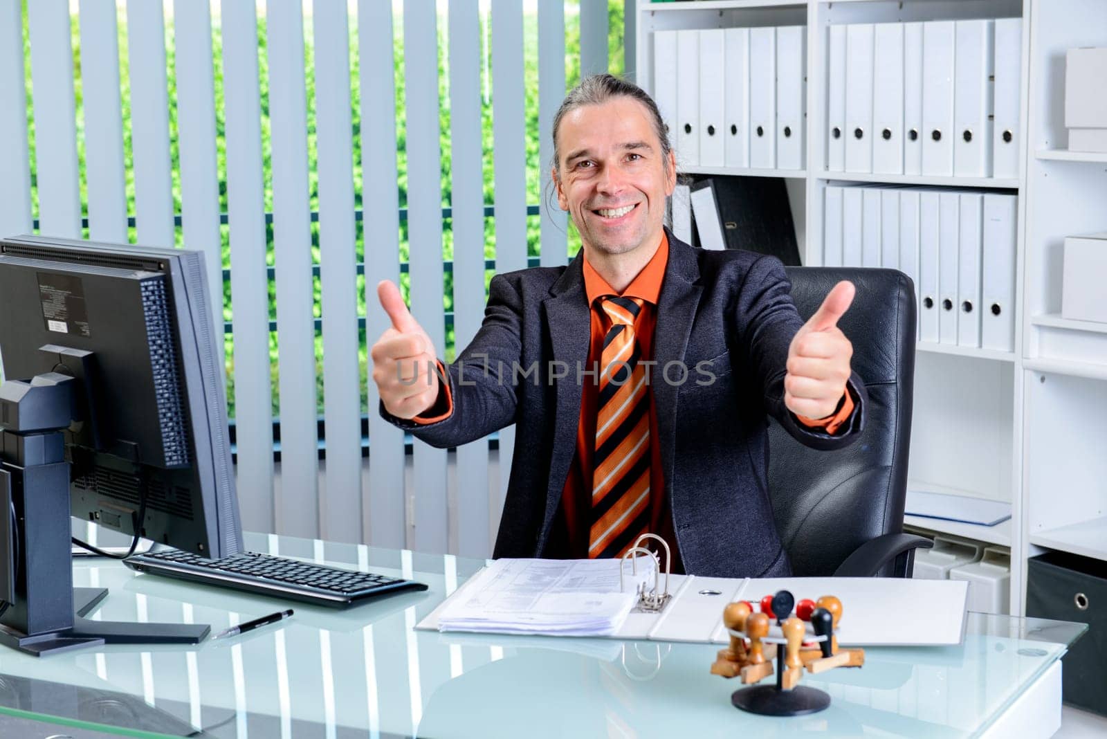 young business man at his desk with thumbs up