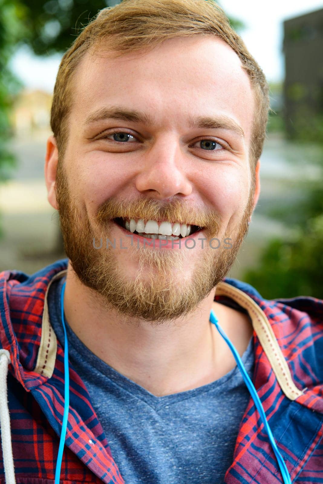 young bearded man in checkered shirt smiling in to the camera