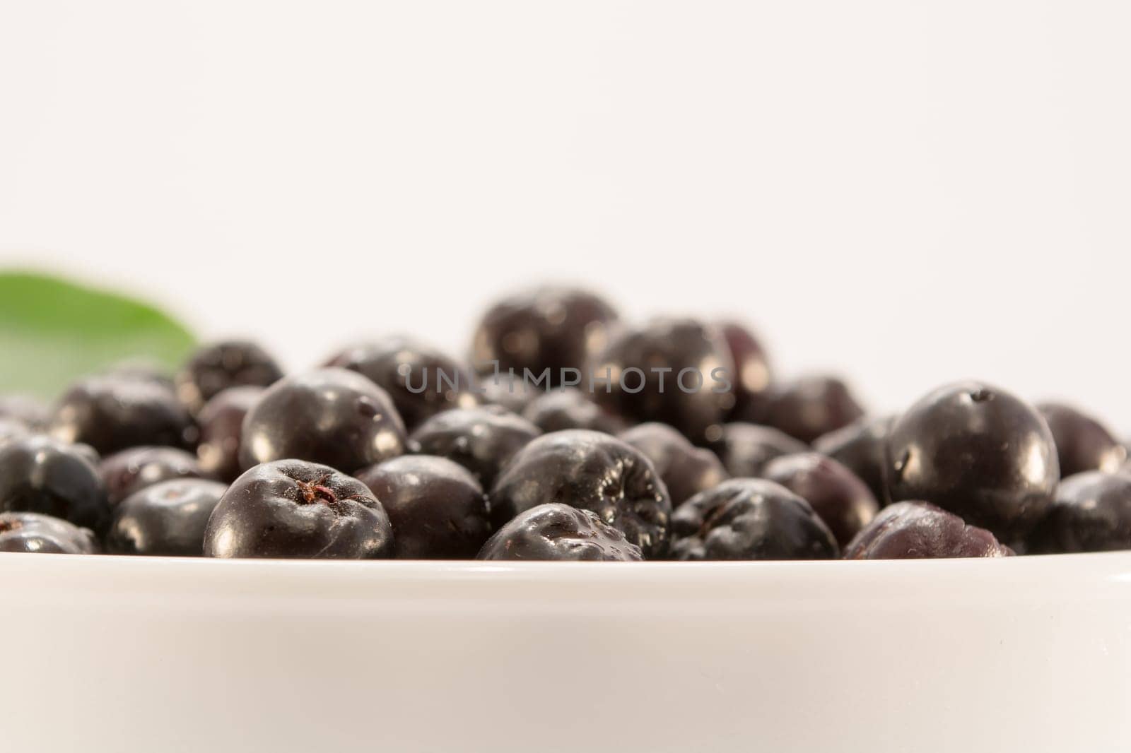 Fresh and tasty aronia in a bowl. Water droplets on fruit are visible