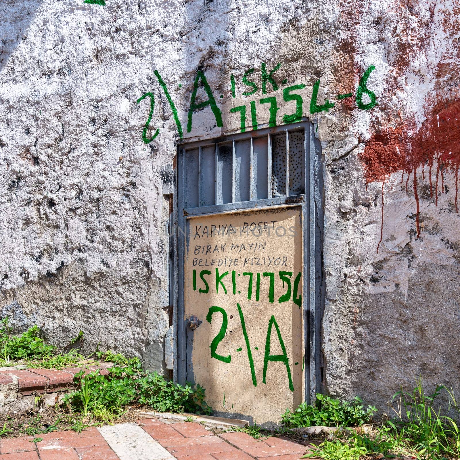 A weathered metal door stands against a textured wall in Istanbul's Balat District, Istanbul, Turkey