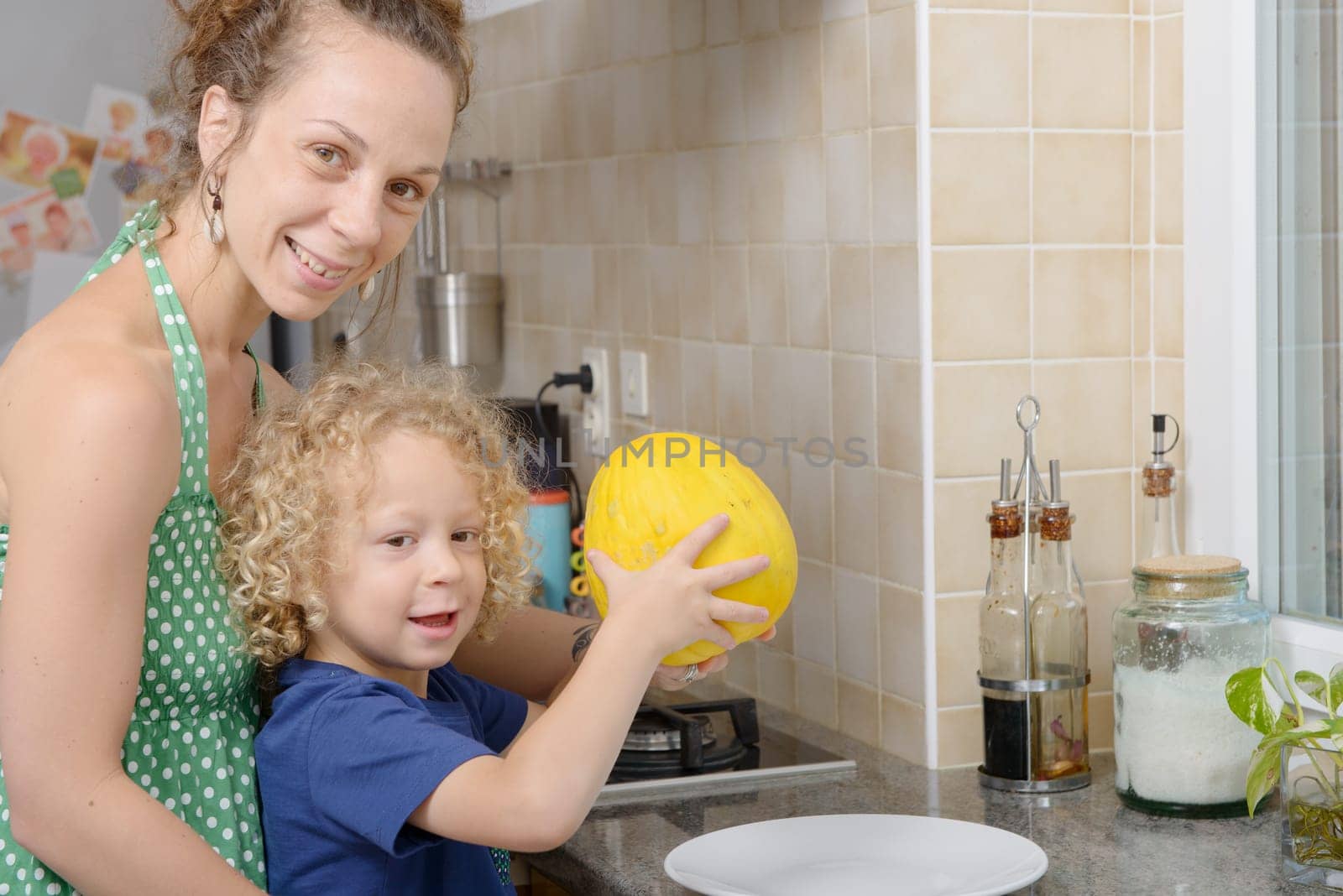 a child and his mother with a melon in kitchen