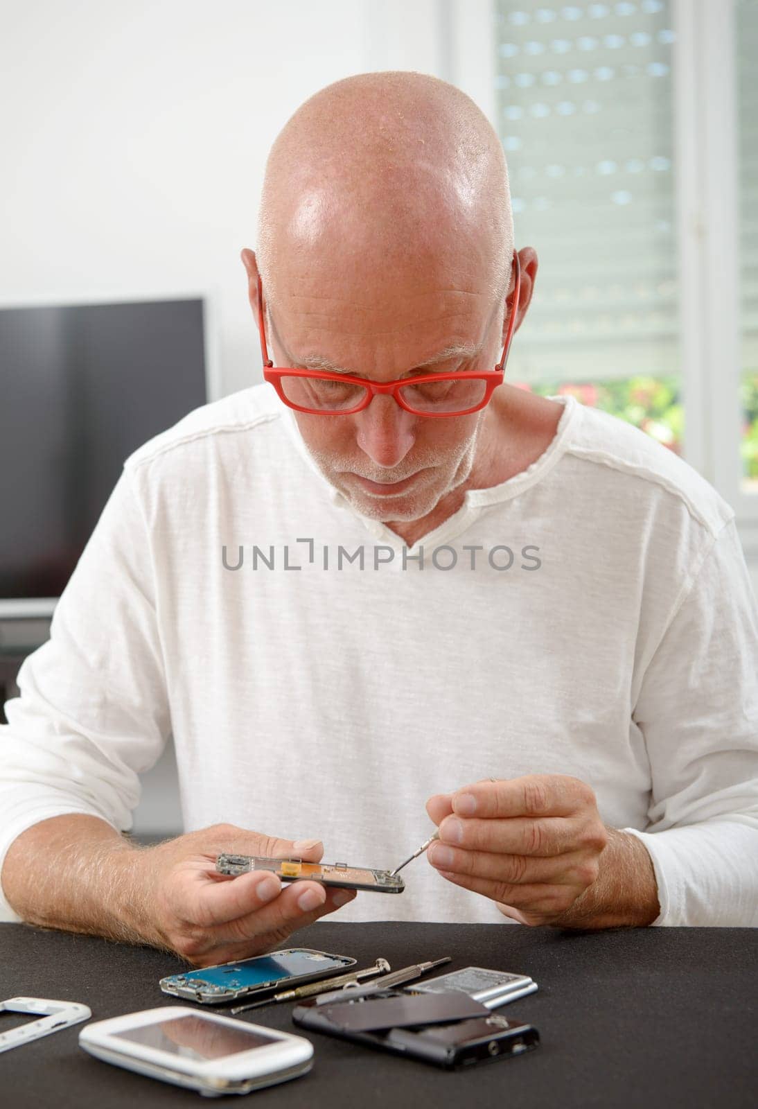 a mature man repaired a smartphone in his home