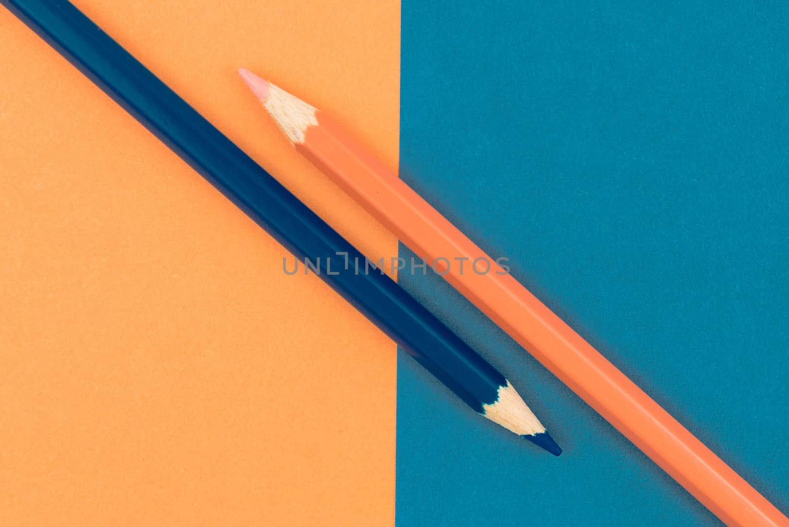 Orange and Dark Blue coloured pencils and paper, abstract contrast conceptual image