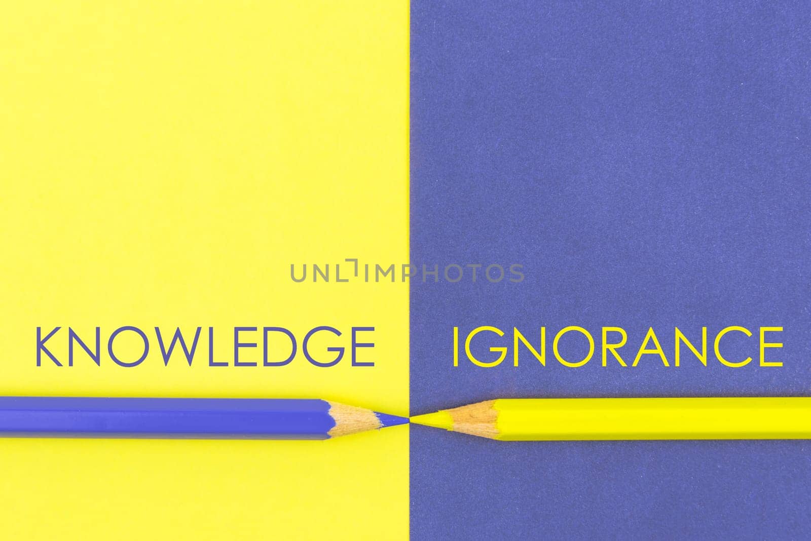 Knowledge versus Ignorance contrast concept . Yellow and Violet coloured pencils and paper.