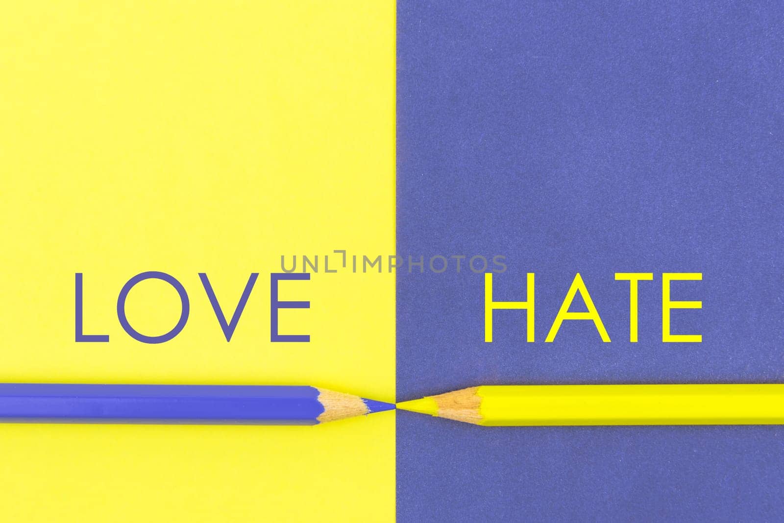 Love versus Hate contrast concept . Yellow and Violet coloured pencils and paper.